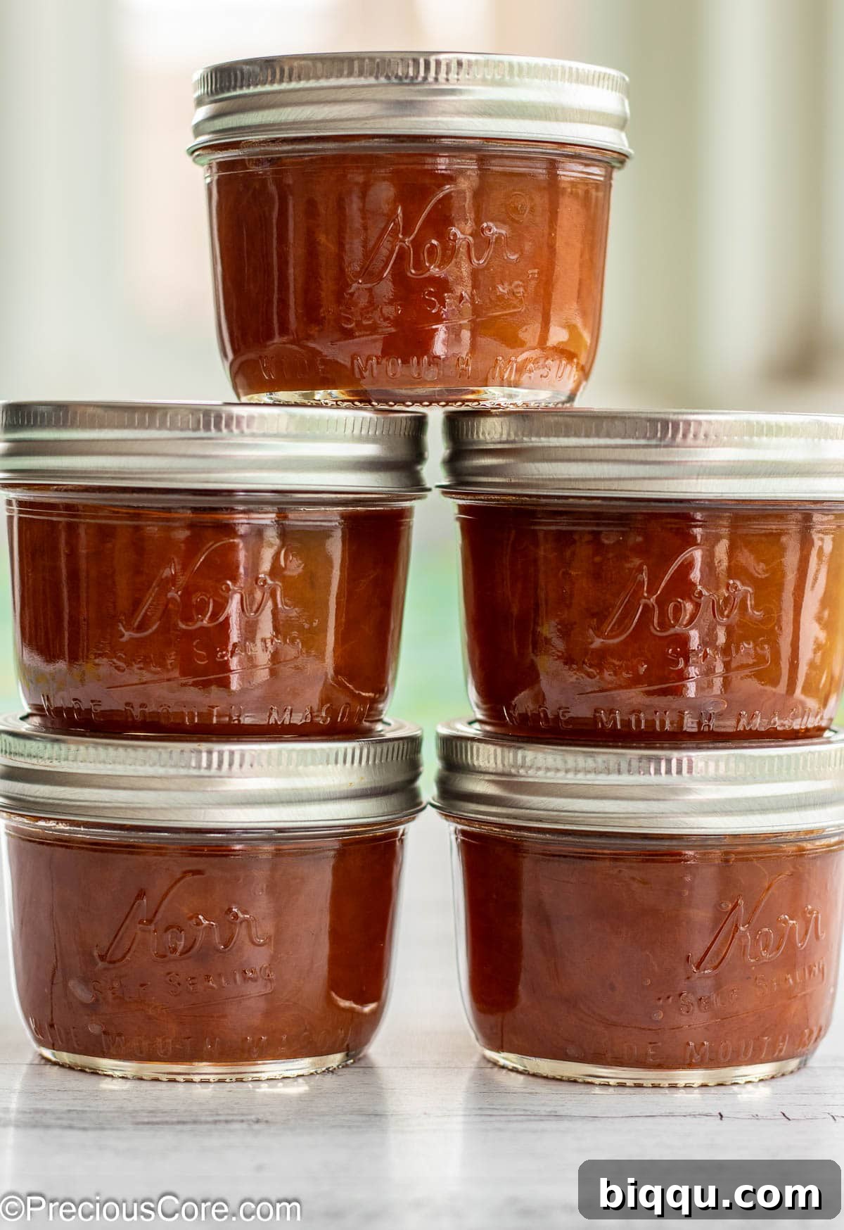 5 jars of fruit preserves stacked on each other.