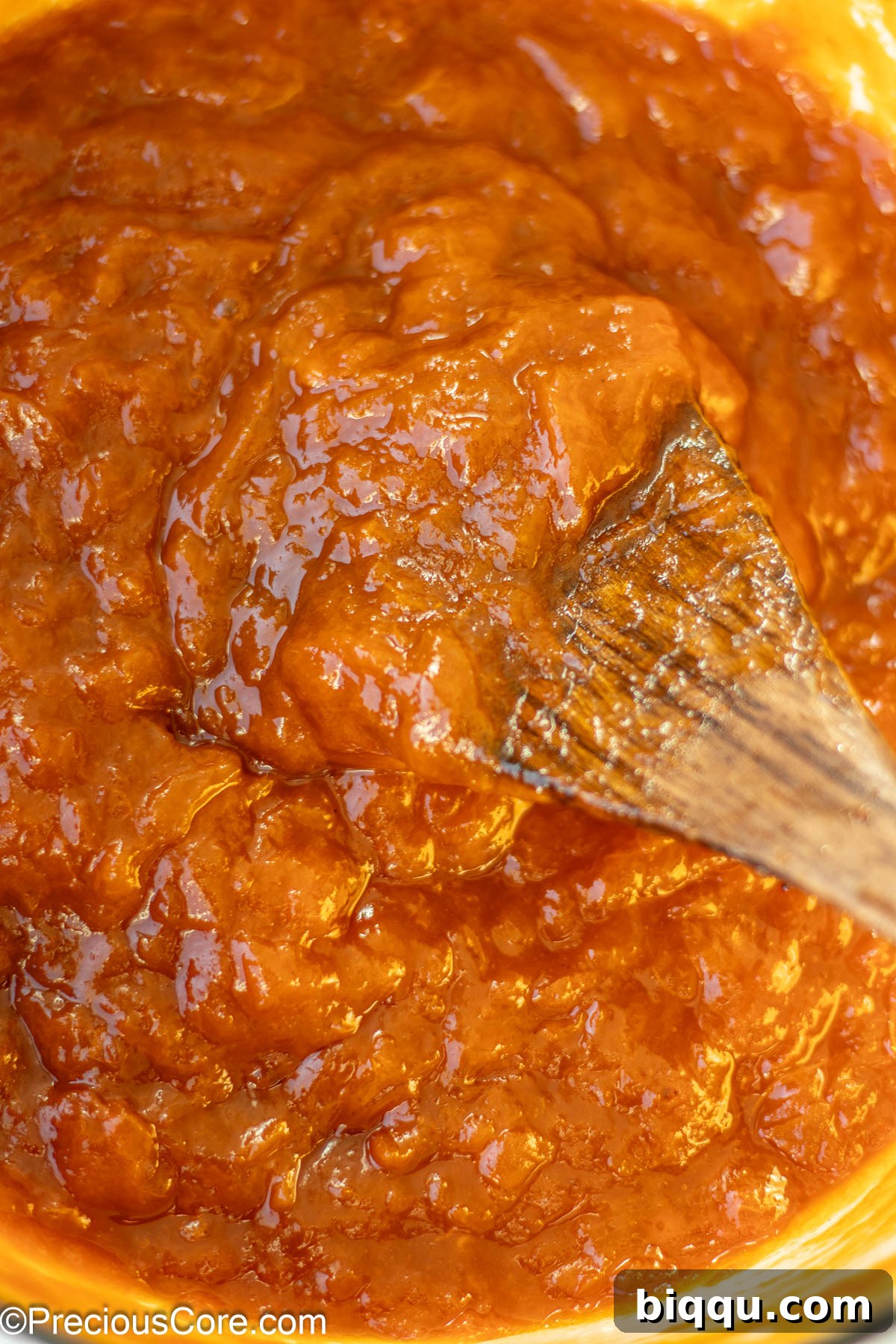 Fully cooked food preserves in a pot with a wooden spoon.