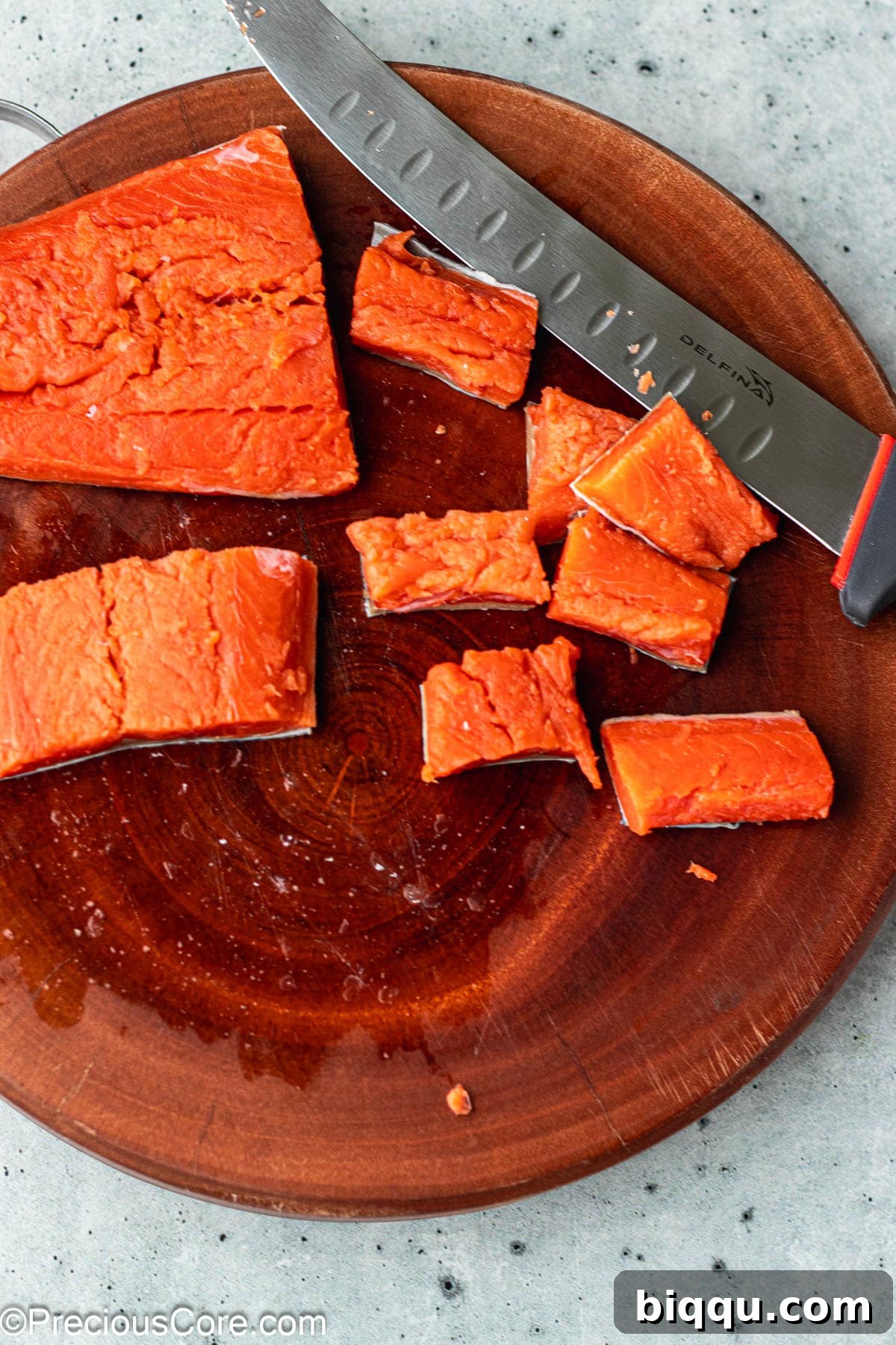 Delicious Salmon Bites 5 Fresh salmon fillet neatly cut into 1-inch cubes on a bamboo chopping board.