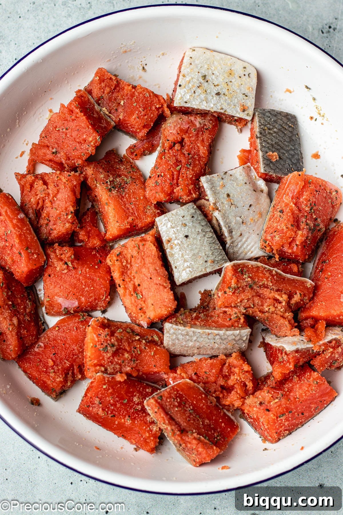 Delicious Salmon Bites 6 Raw salmon cubes in a bowl, visibly coated with a blend of dry seasonings.
