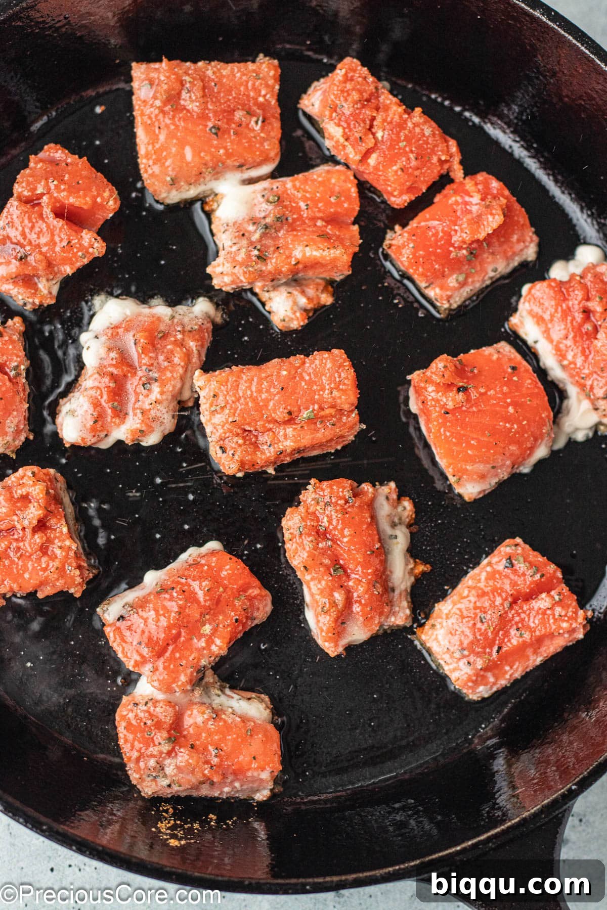 Delicious Salmon Bites 7 Crispy, golden-brown salmon bites cooking in a single layer in a black cast iron skillet.