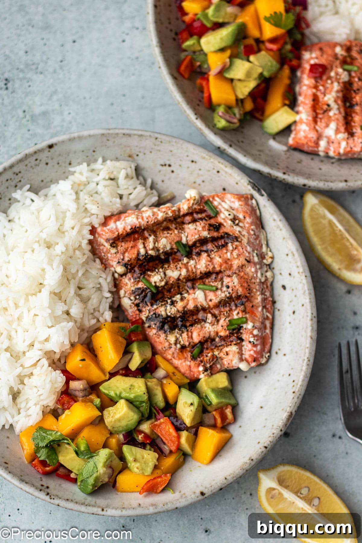 A bowl filled with succulent grilled sockeye salmon, perfectly complemented by a vibrant mango salsa and fluffy rice, ready for a healthy meal.