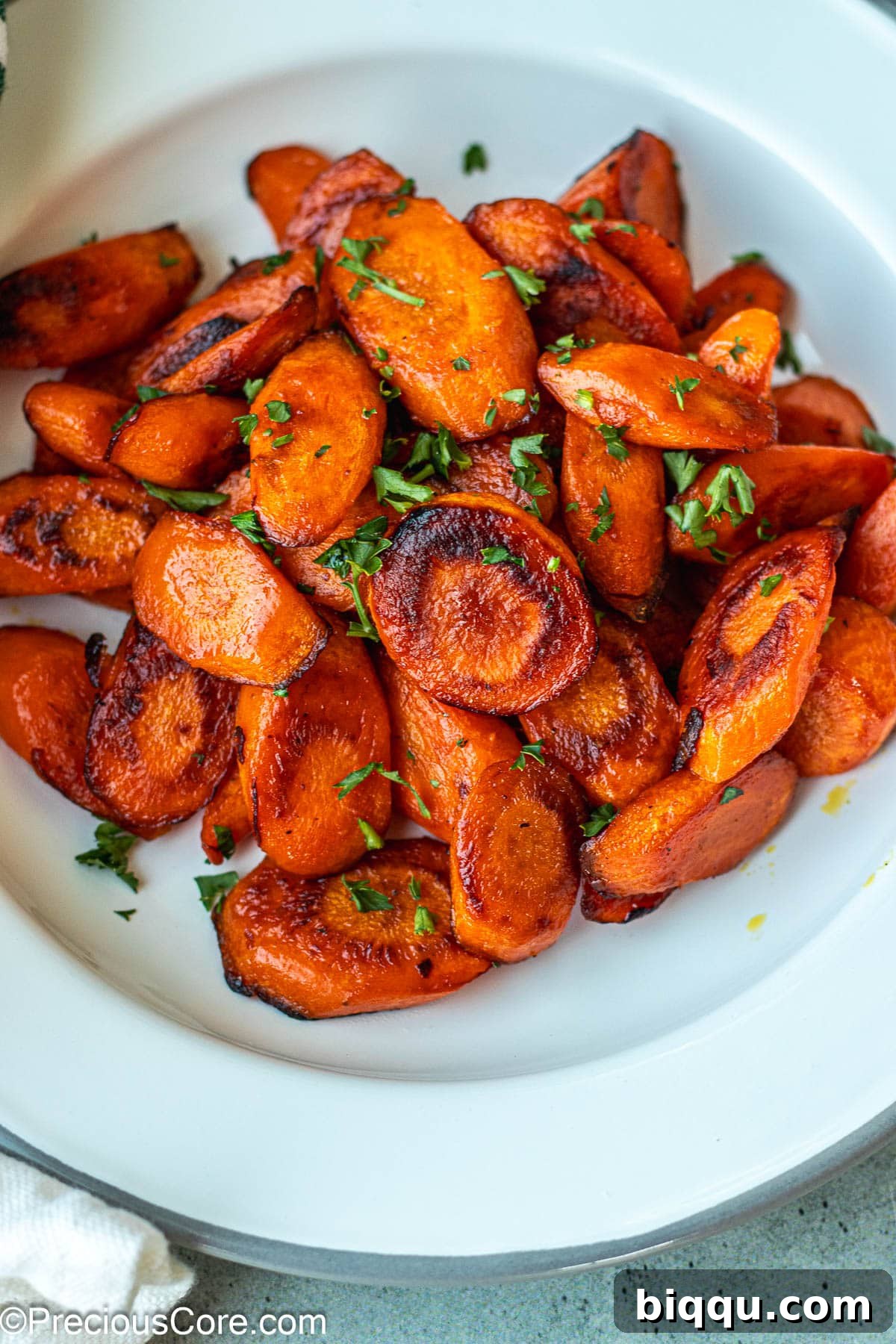 A serving of golden-brown fried carrots on a white plate, garnished with fresh parsley.