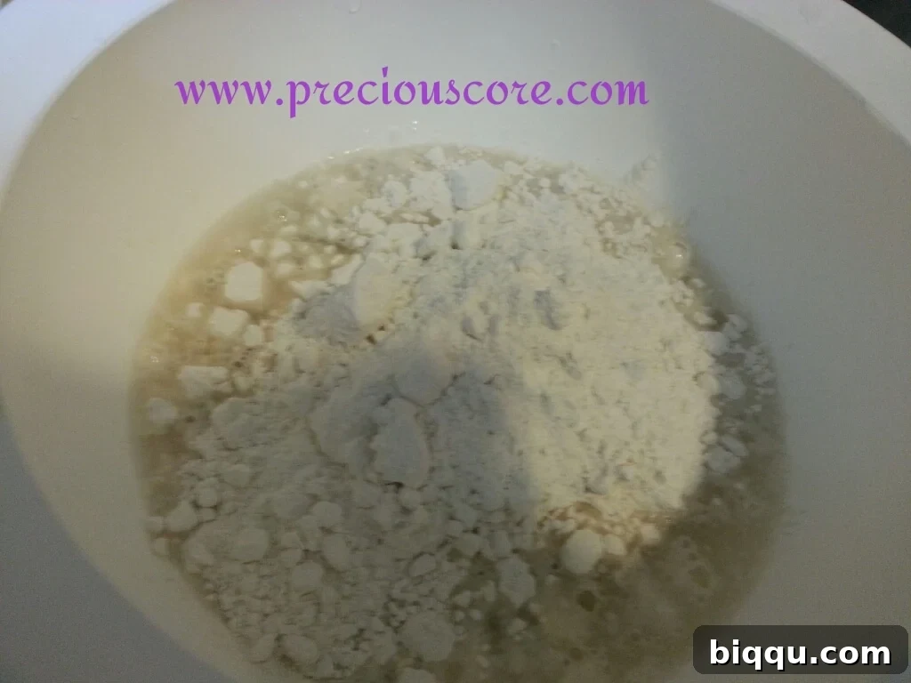 Dry ingredients (flour, sugar, salt, nutmeg, milk powder) added to the yeast mixture in a bowl