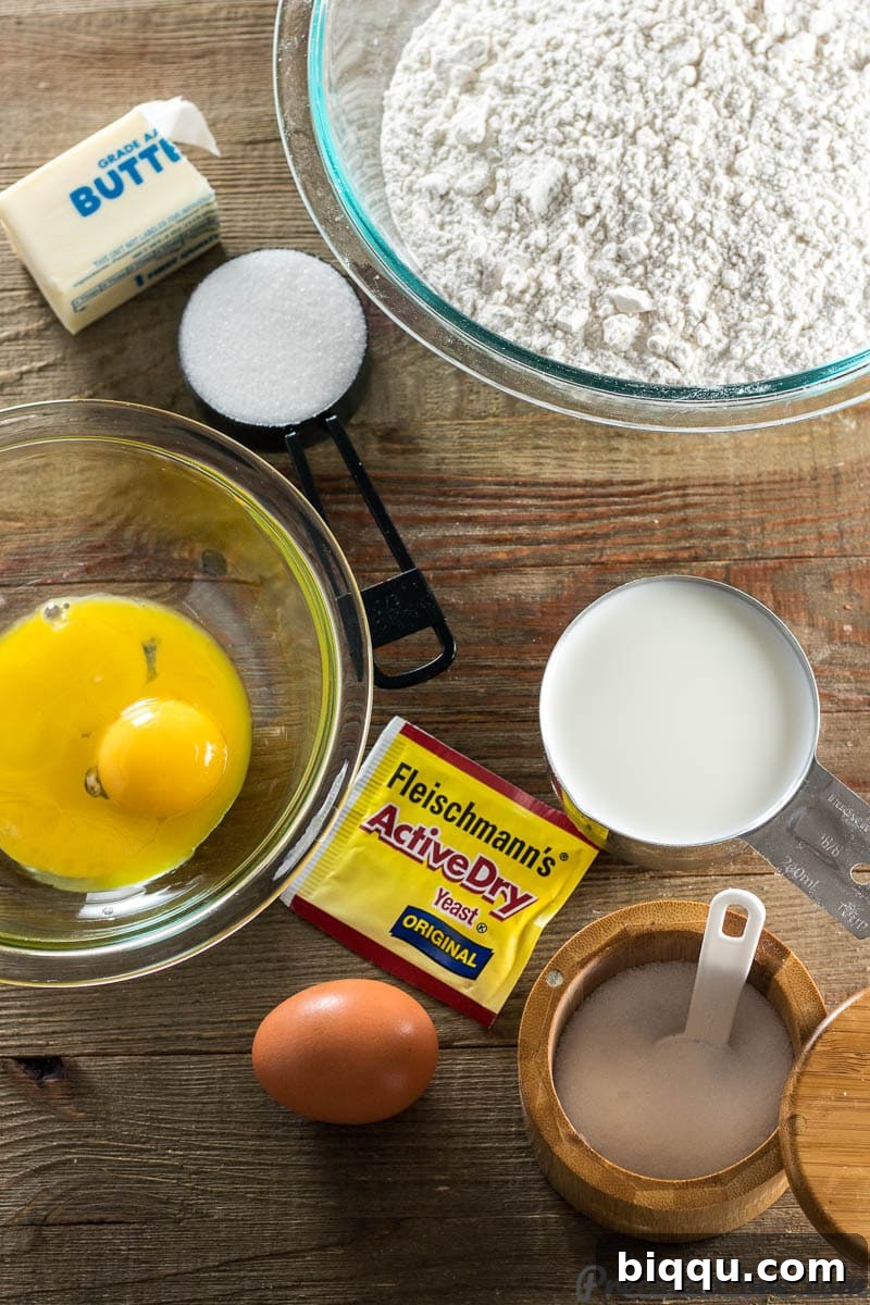 Arrangement of ingredients for sweet dinner rolls: flour, sugar, yeast, milk, butter, salt, and eggs.