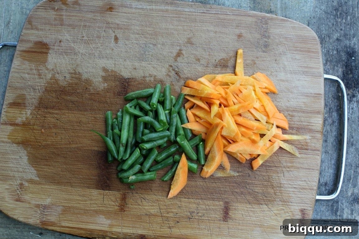 Freshly chopped carrots and green beans, ready to be added to the soup.
