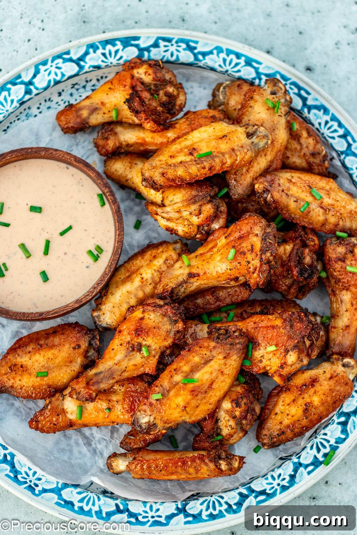Crispy Baked Dry Rub Chicken Wings served alongside a bowl of creamy ranch dressing, garnished with fresh herbs.