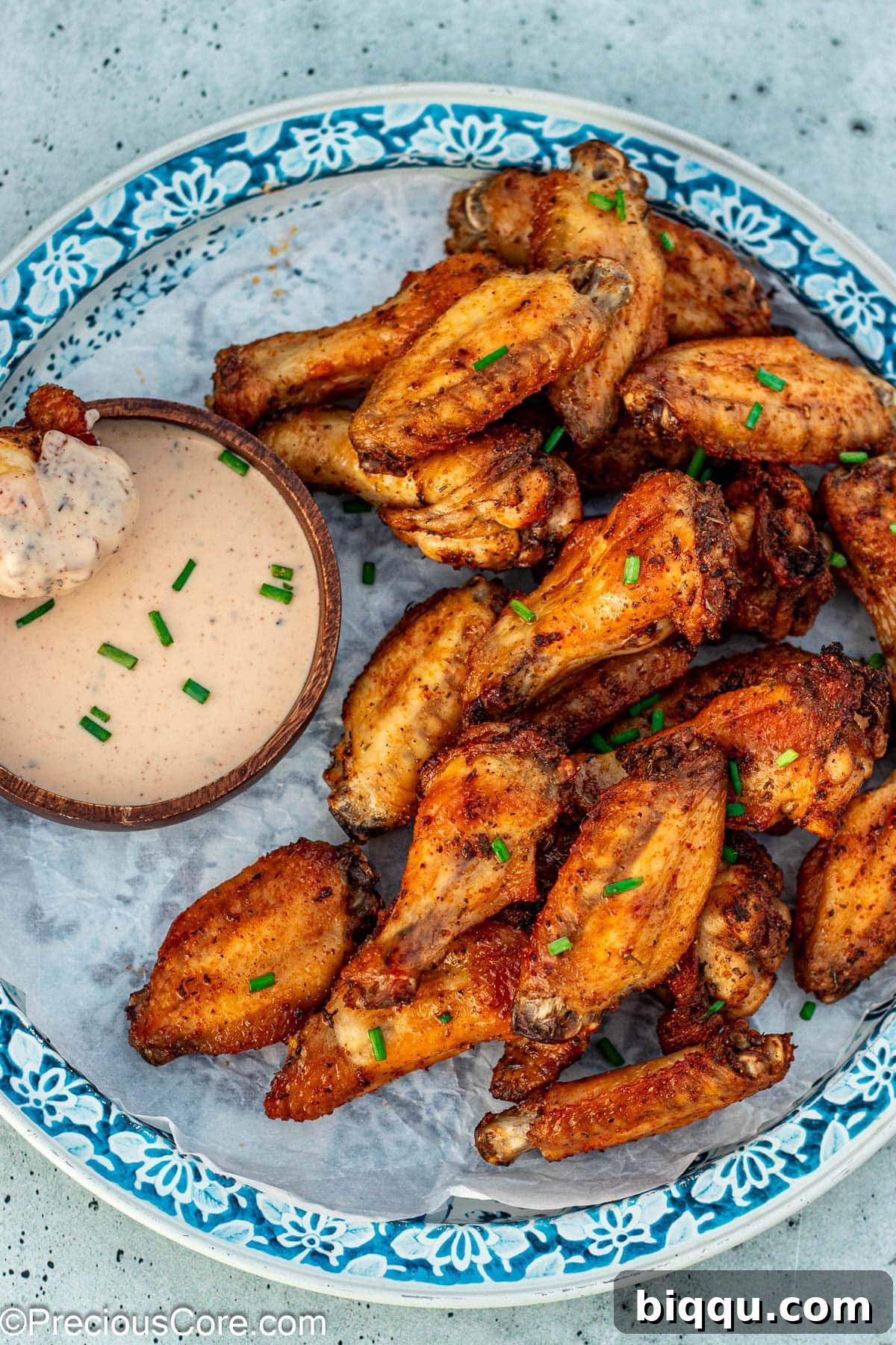 A perfectly baked dry rub chicken wing dipped in creamy ranch dressing, held by a hand.