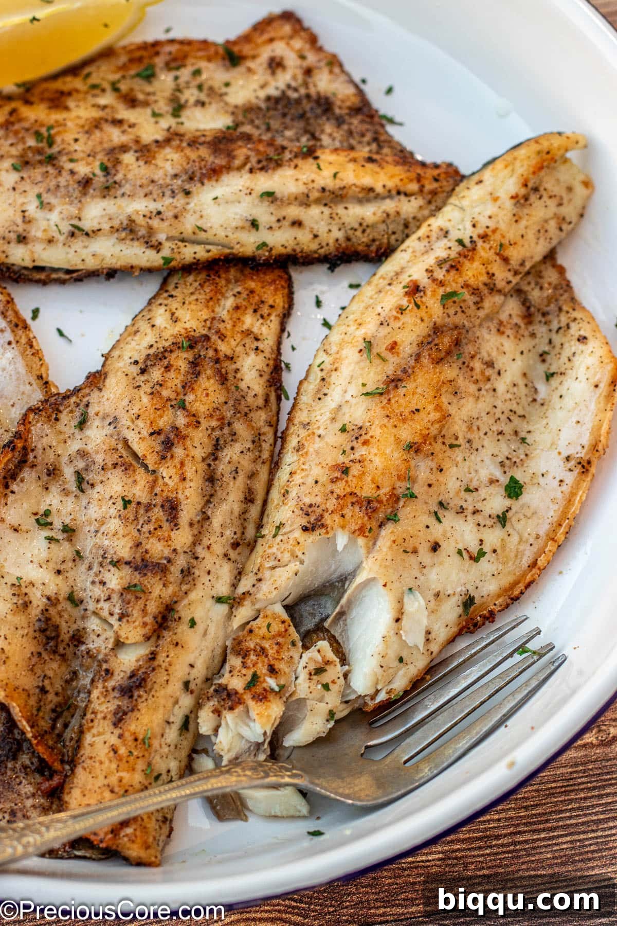 A fork gently flaking cooked sea bass to demonstrate its tender texture.