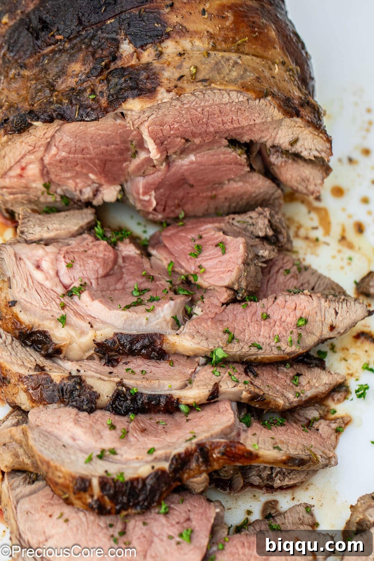 A beautifully sliced roasted boneless leg of lamb, revealing its tender, juicy interior.