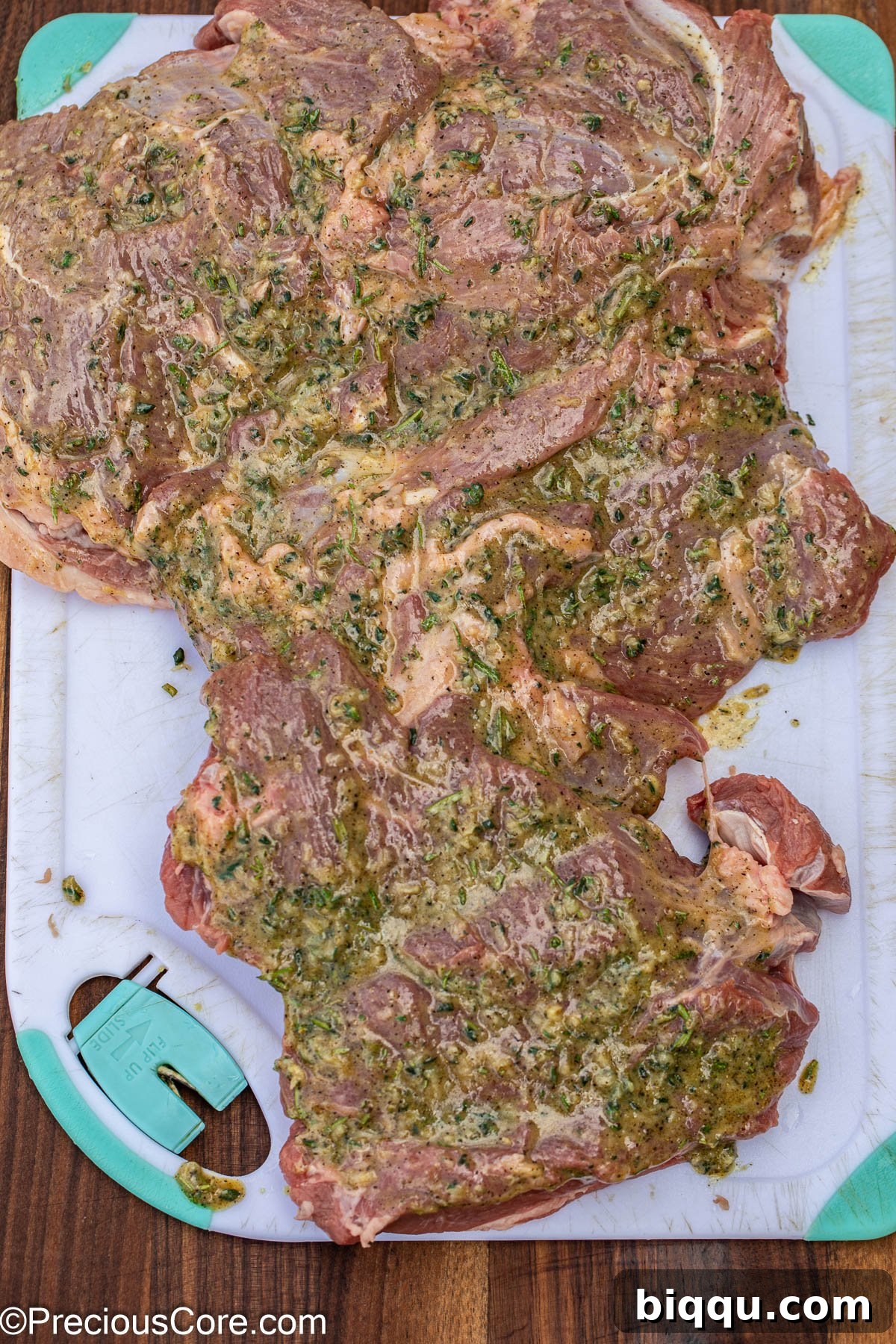 A large piece of lamb meat being generously brushed with the herb and garlic marinade.