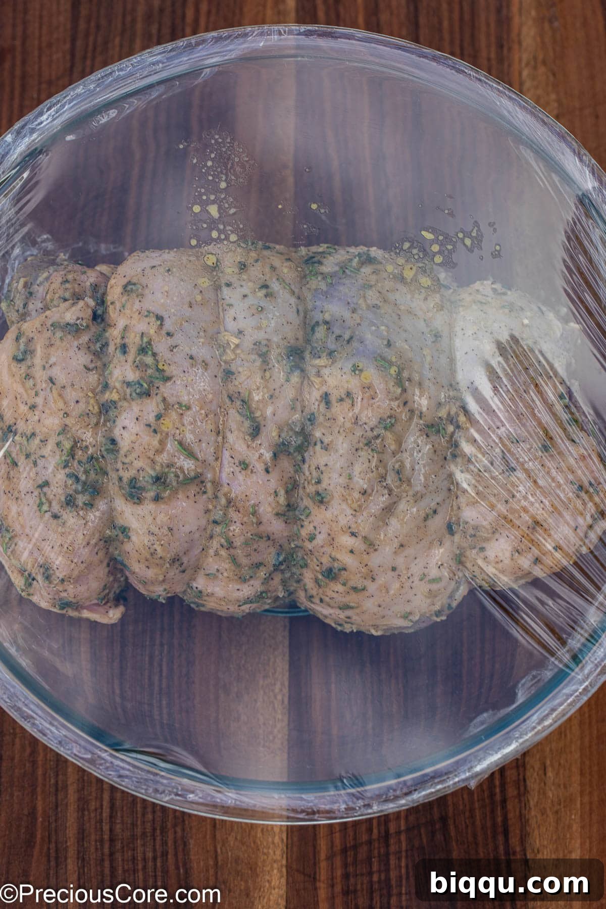 The lamb resting in a mixing bowl, covered for marination.