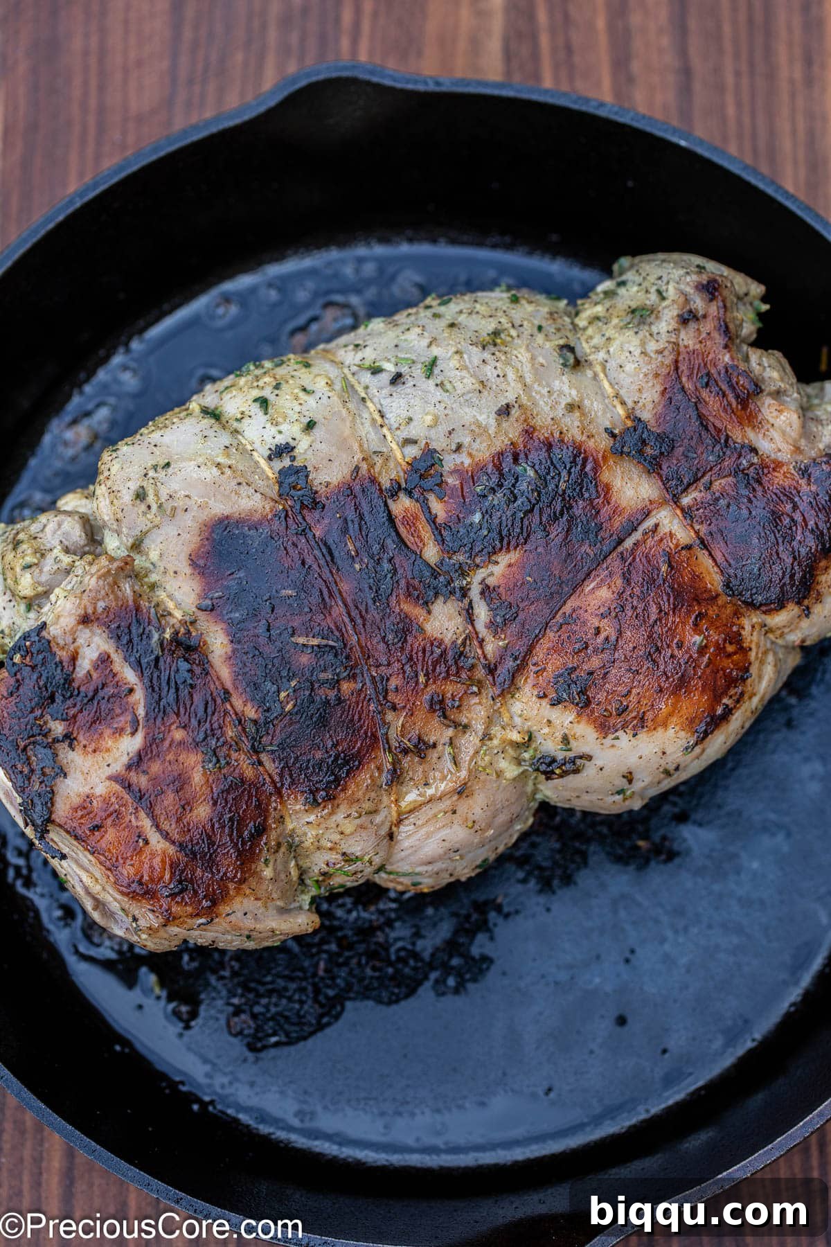 The boneless lamb leg beautifully seared in a cast iron skillet, showing a rich brown crust.
