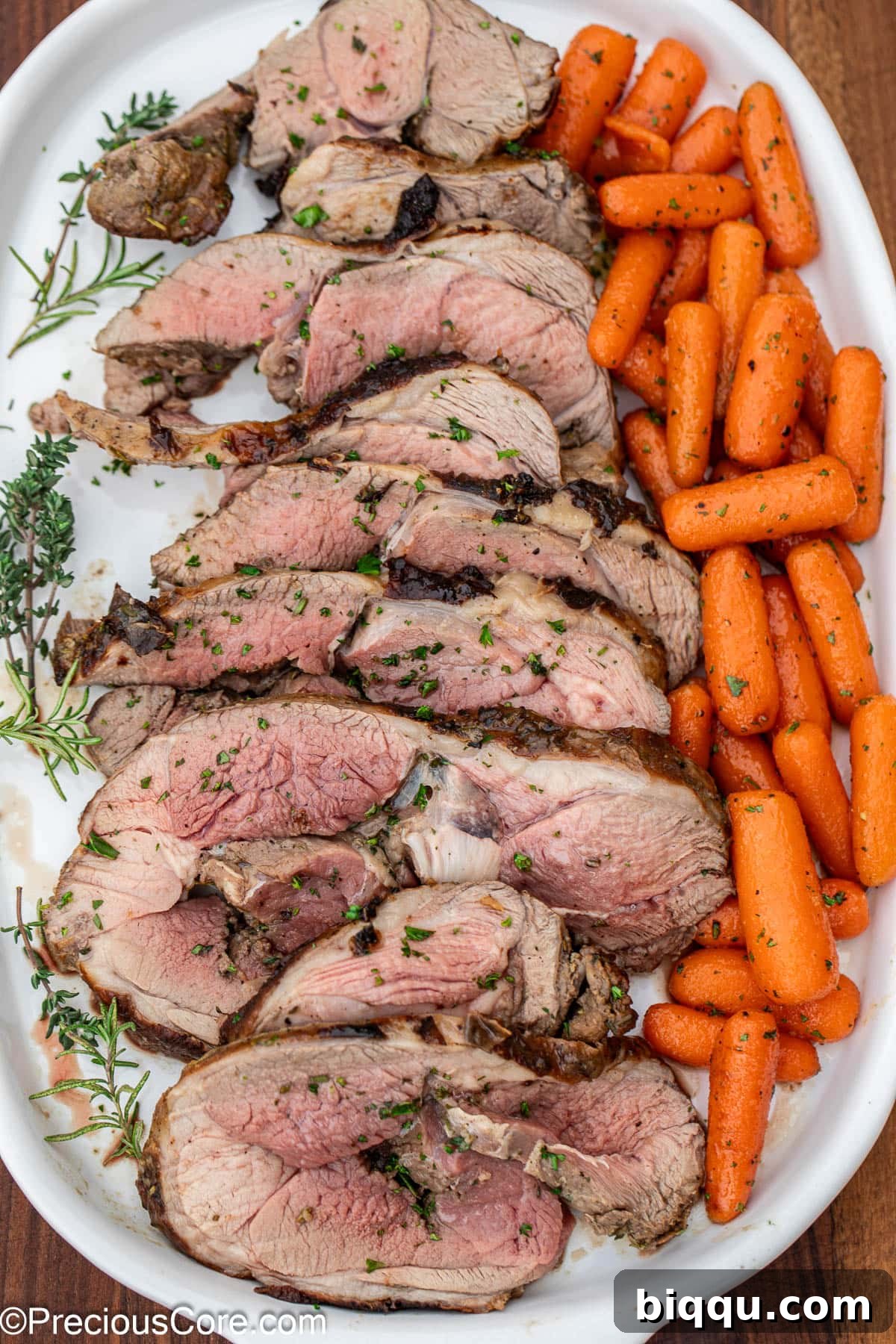 Perfectly sliced roast lamb served on a white tray with glazed carrots, ready for guests.