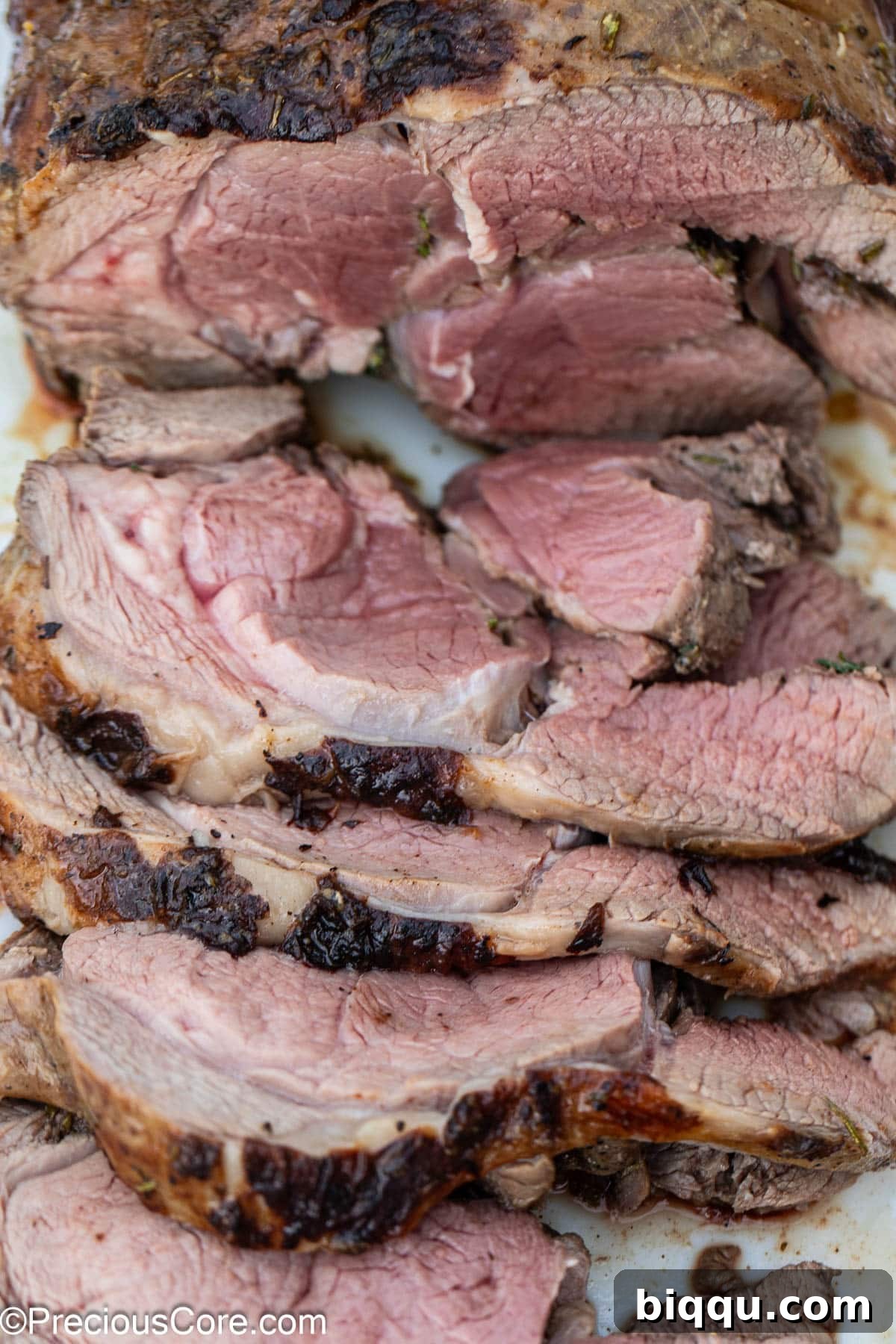 Freshly sliced lamb roast arranged on a cutting board, showcasing its juicy interior.