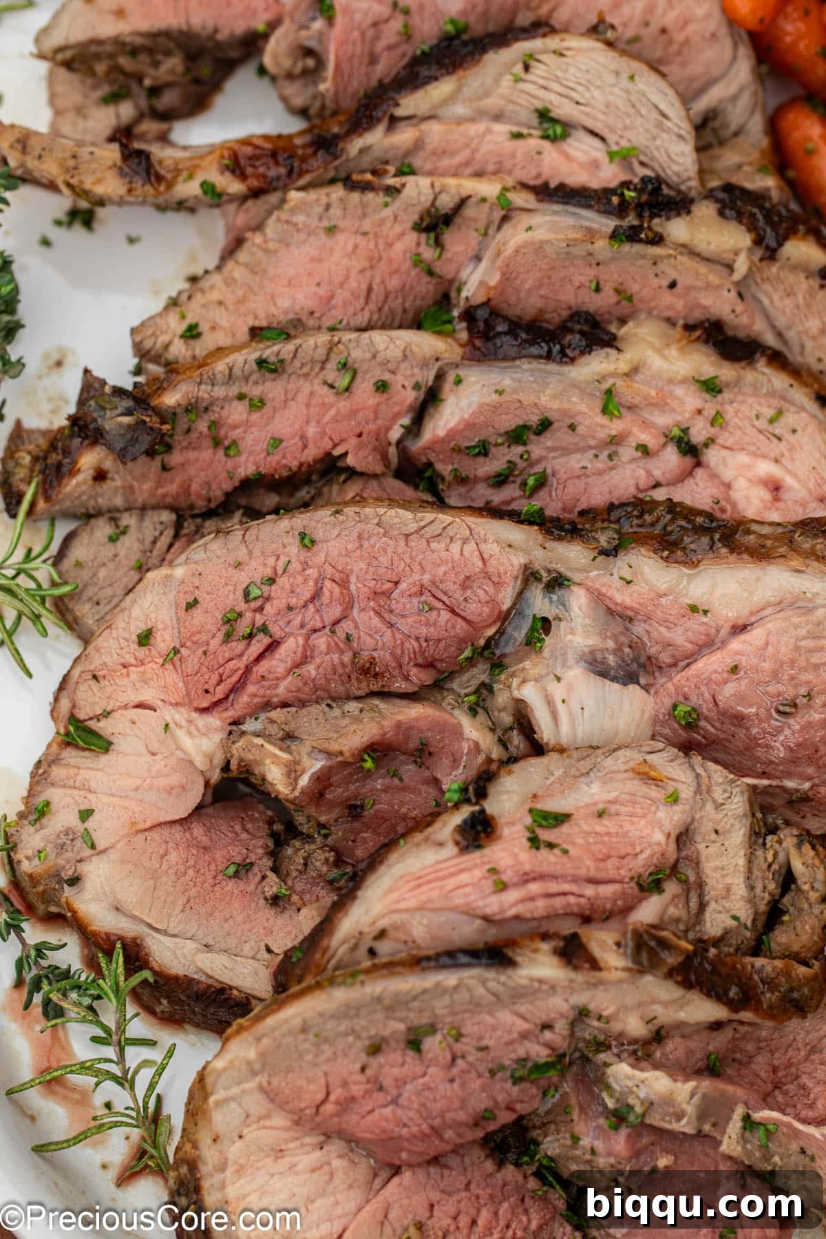 A close-up shot of perfectly cooked and sliced lamb roast, glistening with juices.