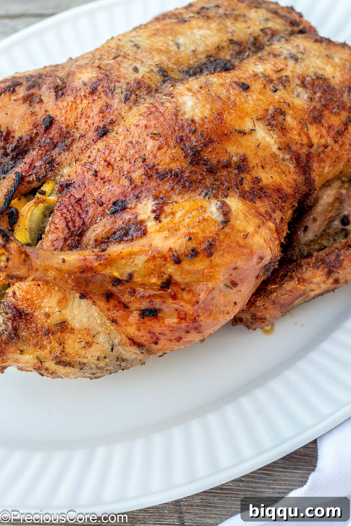 Herb Roasted Duck on a white serving tray, garnished with fresh herbs and lemon slices.