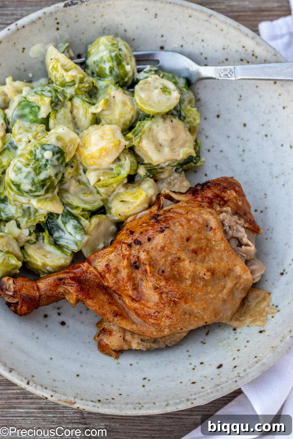 Sliced roasted duck in a bowl with creamy Brussels sprouts.