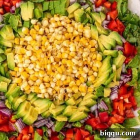 A vibrant corn, avocado, and mixed vegetable salad on a platter, ready to serve.