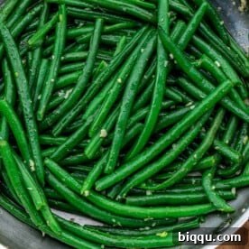 Square image of green beans coated in garlic butter, an irresistible side dish.
