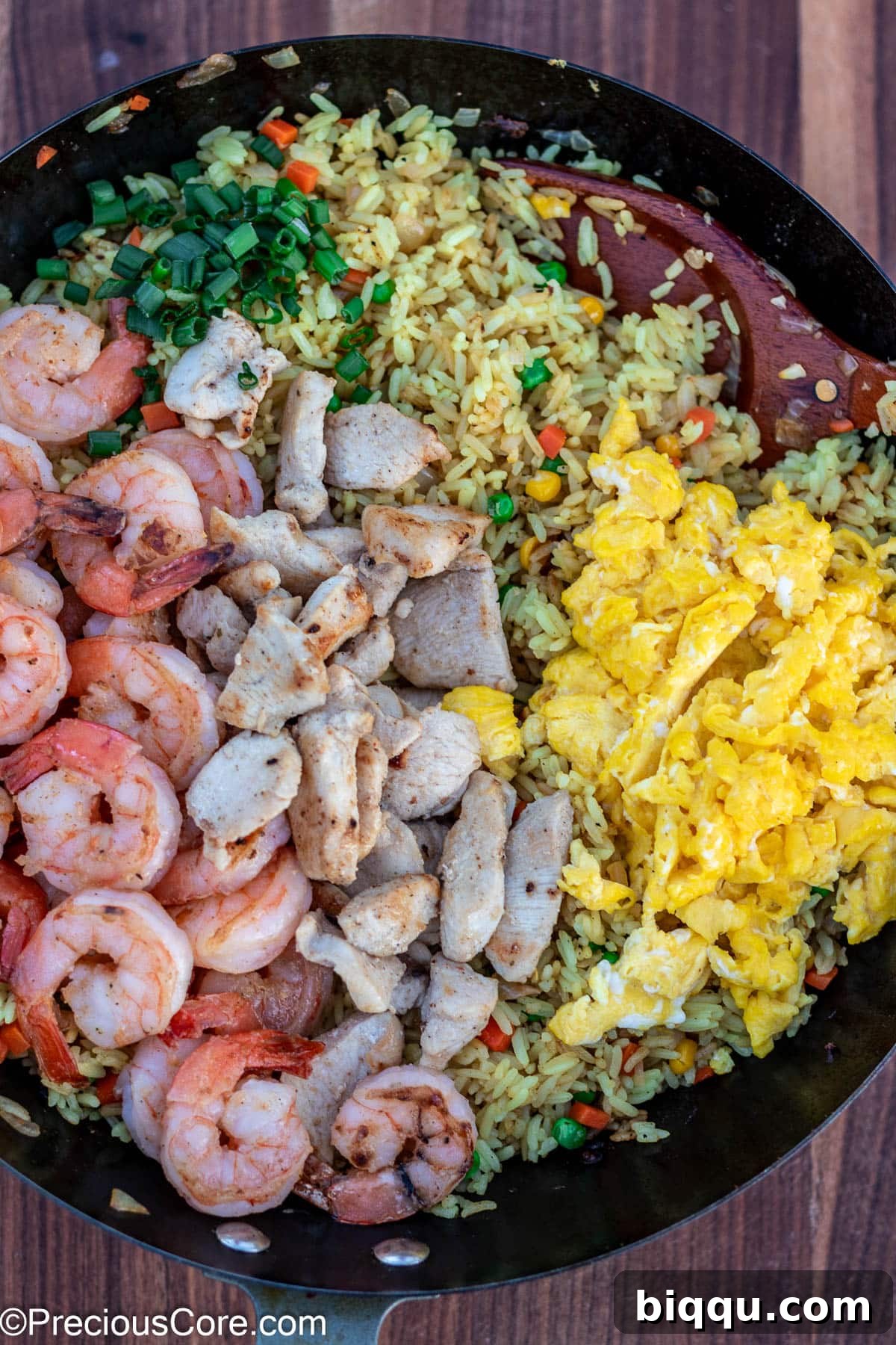 Final stage of fried rice topped with shrimp and chicken, ready to be served.