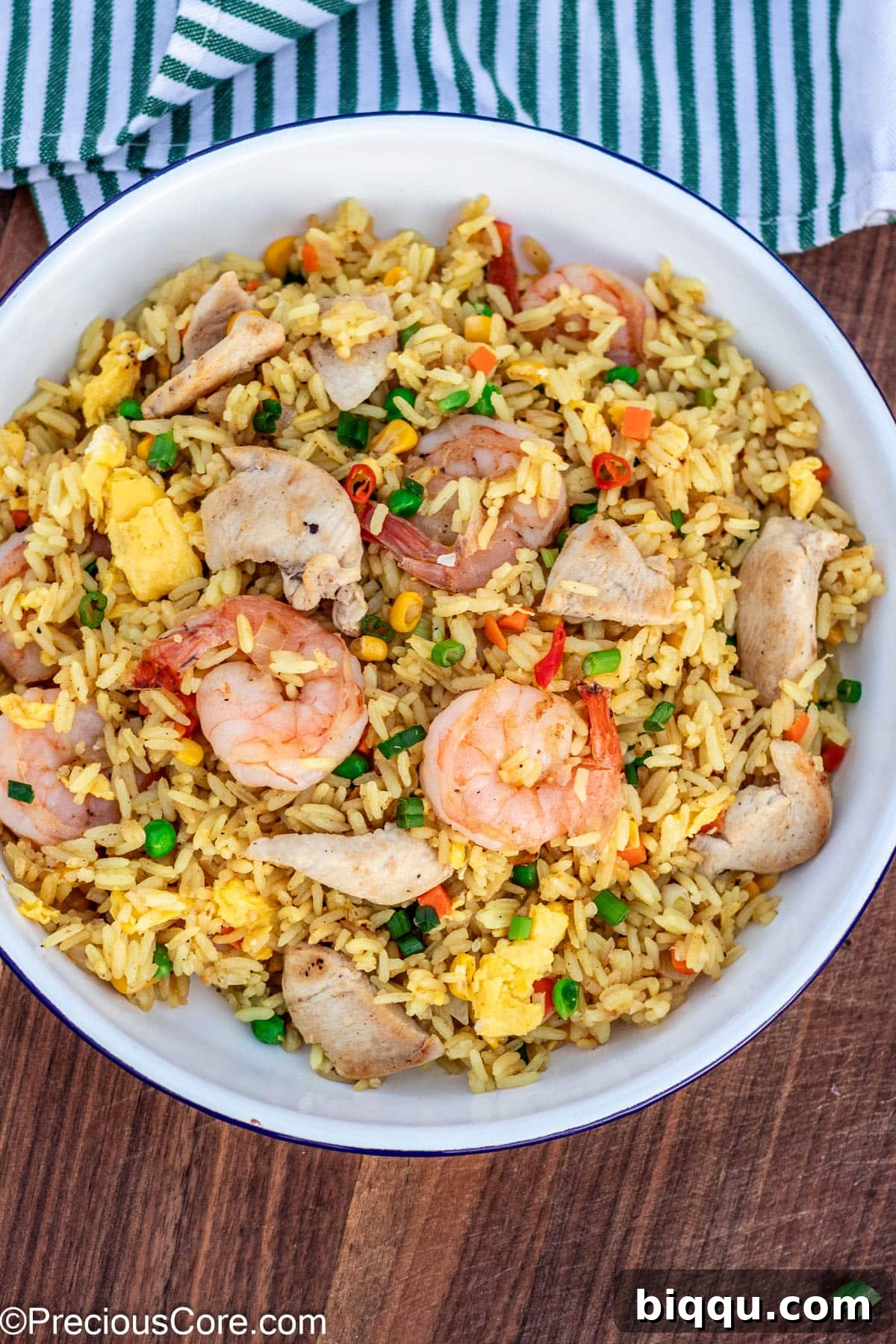 Fried rice in a plate, topped with generous portions of chicken and shrimp.