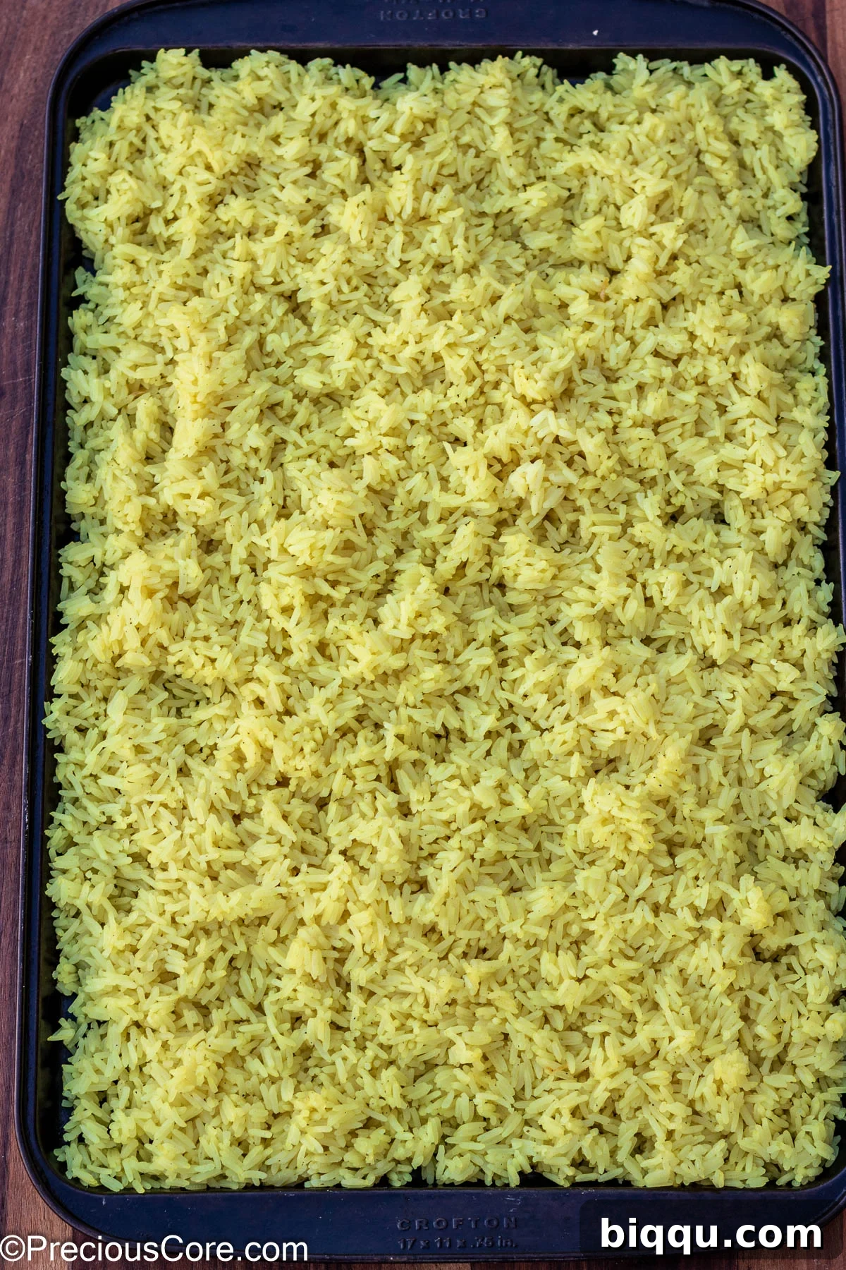 Cooked jasmine rice spread evenly on a large tray, ready for frying.