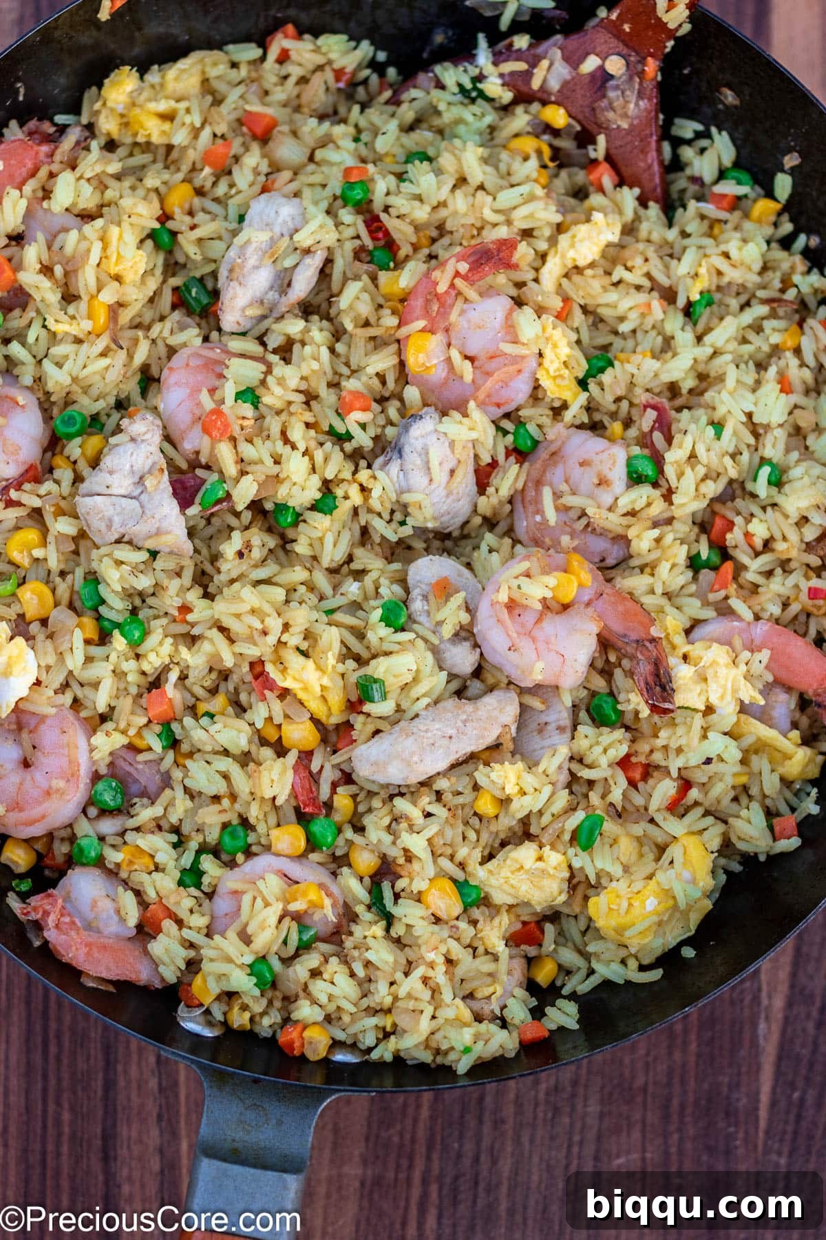 Fried rice being actively stir-fried in a large wok over high heat.