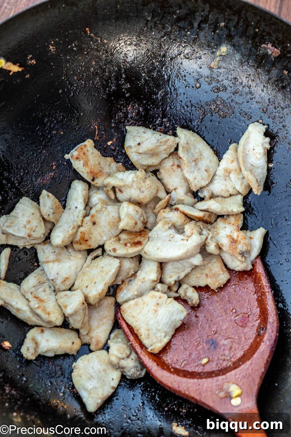 Golden-brown chicken pieces cooking in a wok.
