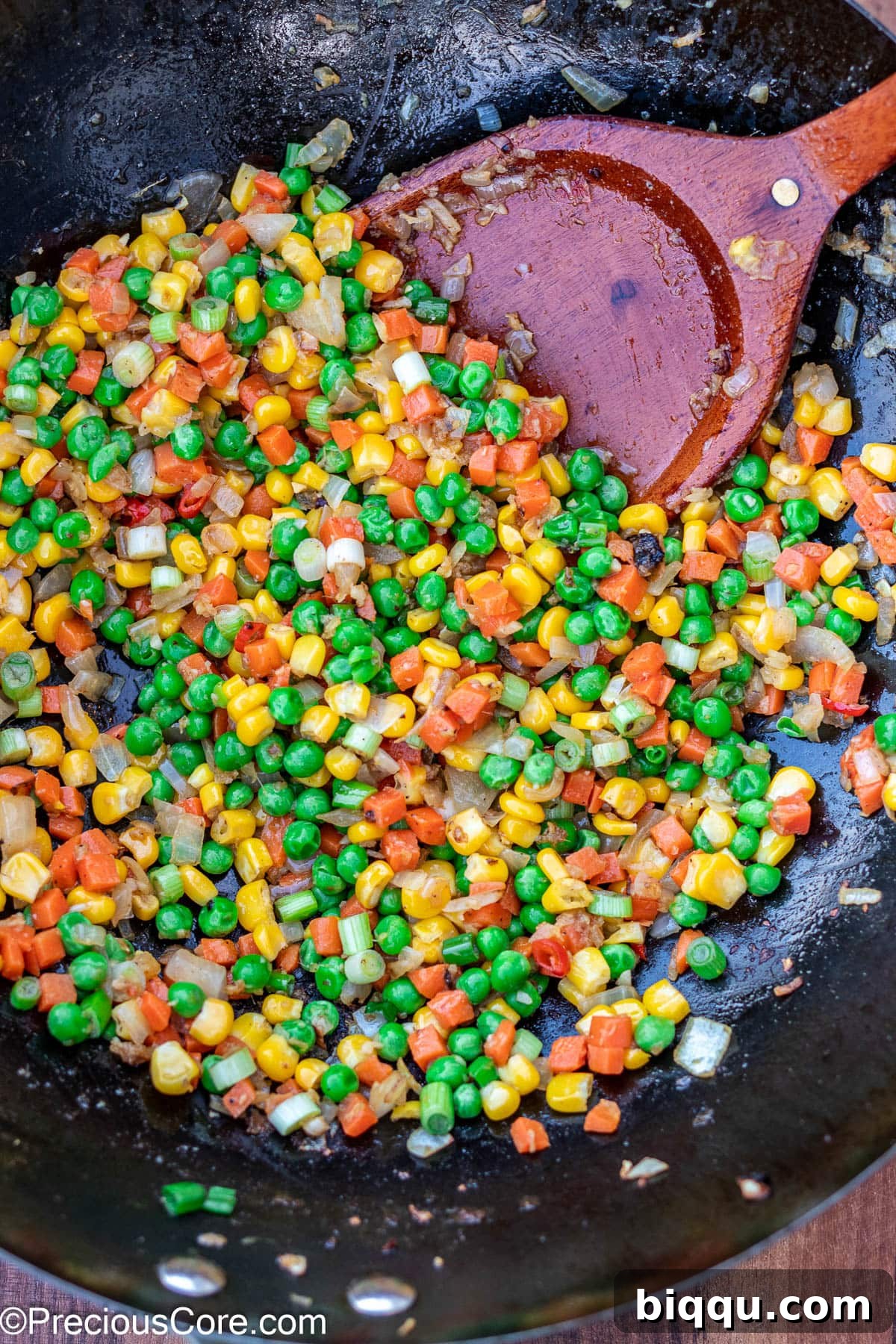 Mixed vegetables sizzling in a wok with aromatics.
