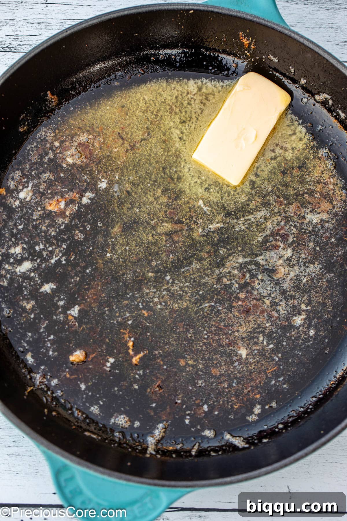 A cast iron skillet with butter slowly melting and bubbling over medium heat.