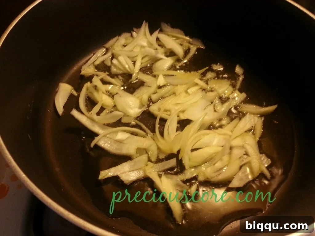 Sautéing Onions for the Flavor Base Chopped onions sautéing in olive oil in a pan, beginning to brown.