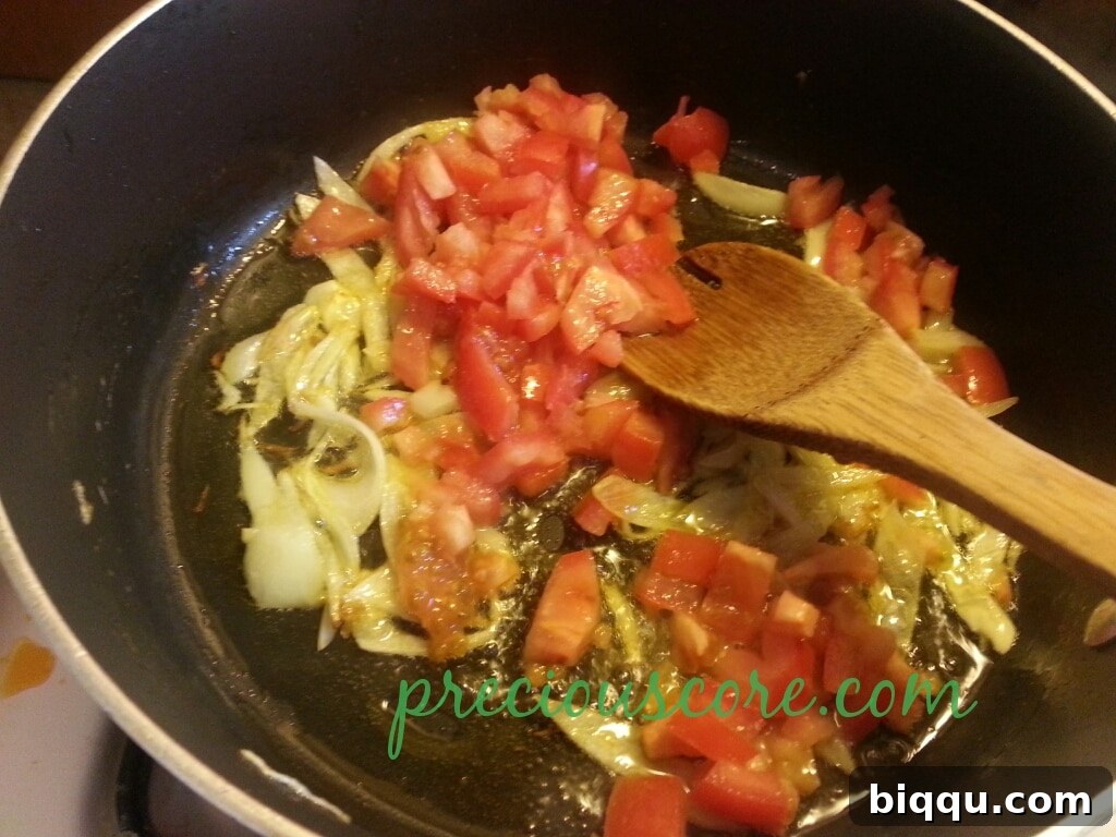 Simmering Tomatoes for Depth of Flavor Tomatoes and onions cooking down in the pan, creating a rich sauce.