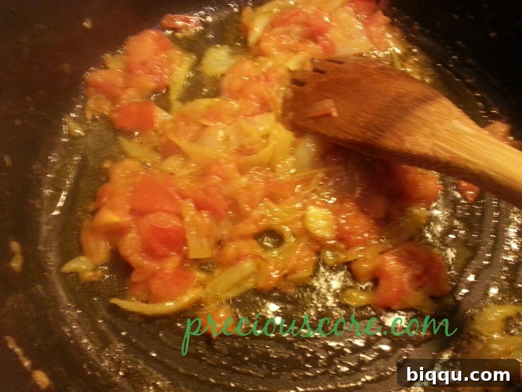 Infusing Aromatics and Seasoning Garlic, ginger, and celery paste, along with crayfish seasoning cube and salt, added to the tomato-onion mixture.