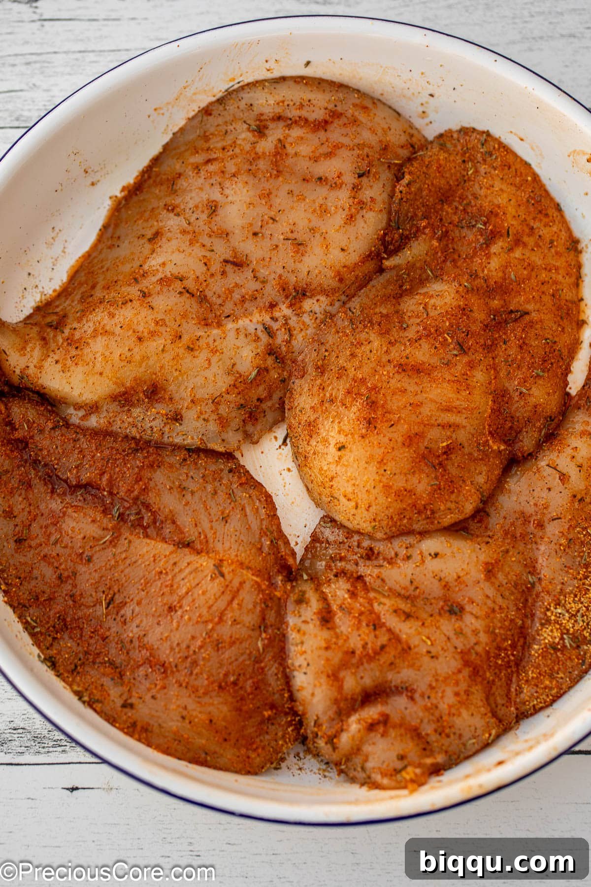 Seasoned chicken breasts in a bowl.
