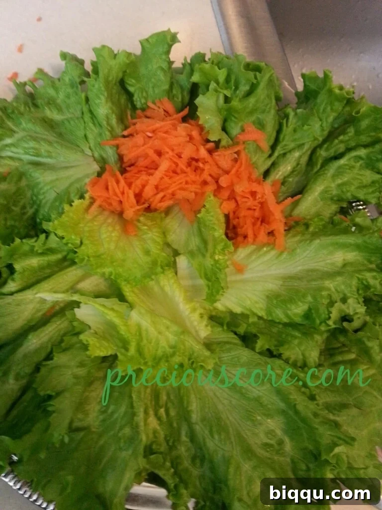 Vibrantly shredded carrots carefully added to the crisp lettuce base for a colorful salad