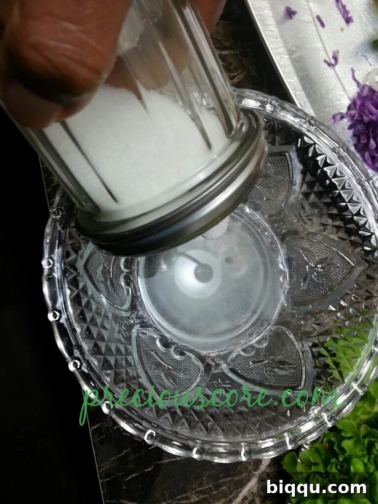 Sugar and salt added to white vinegar in a bowl, beginning the dressing mixture