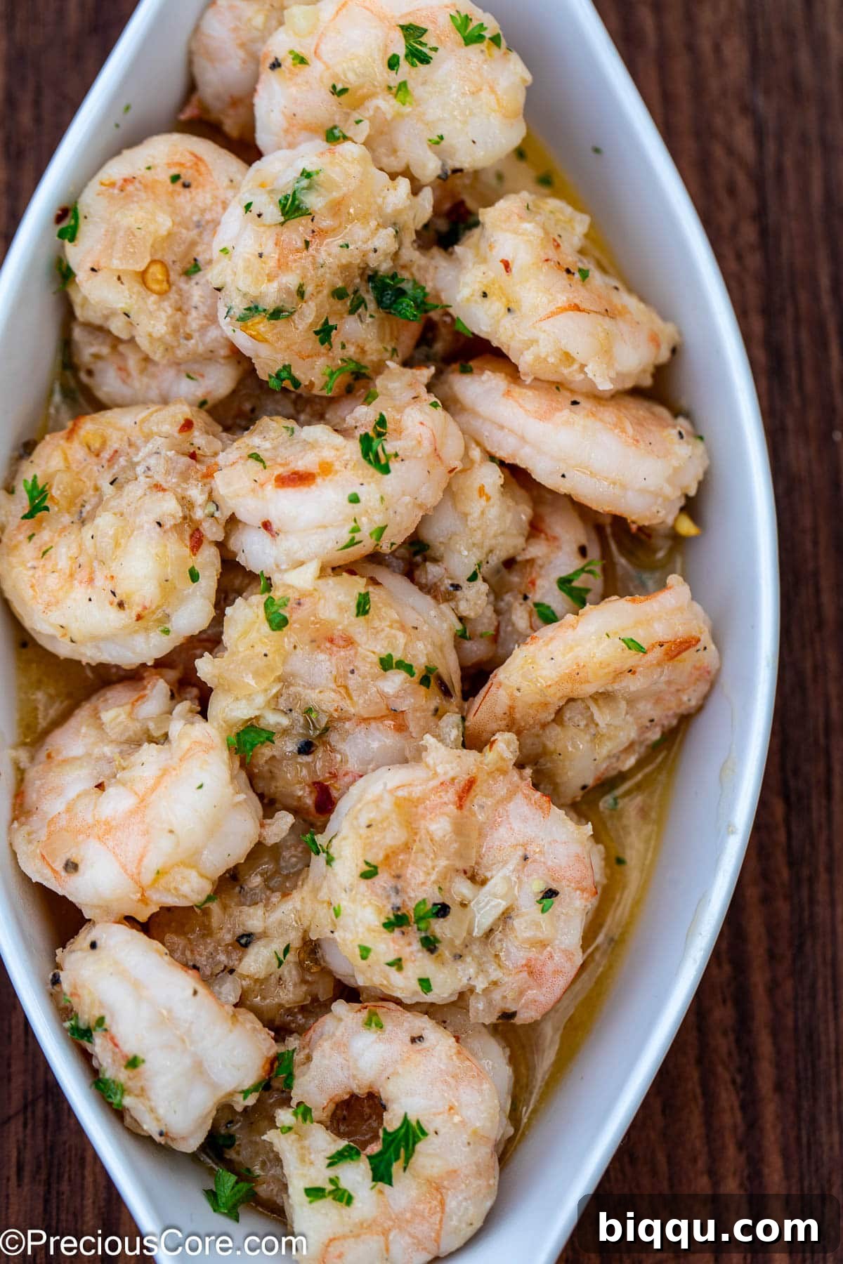A beautifully plated serving of shrimp in white wine sauce garnished with fresh herbs.