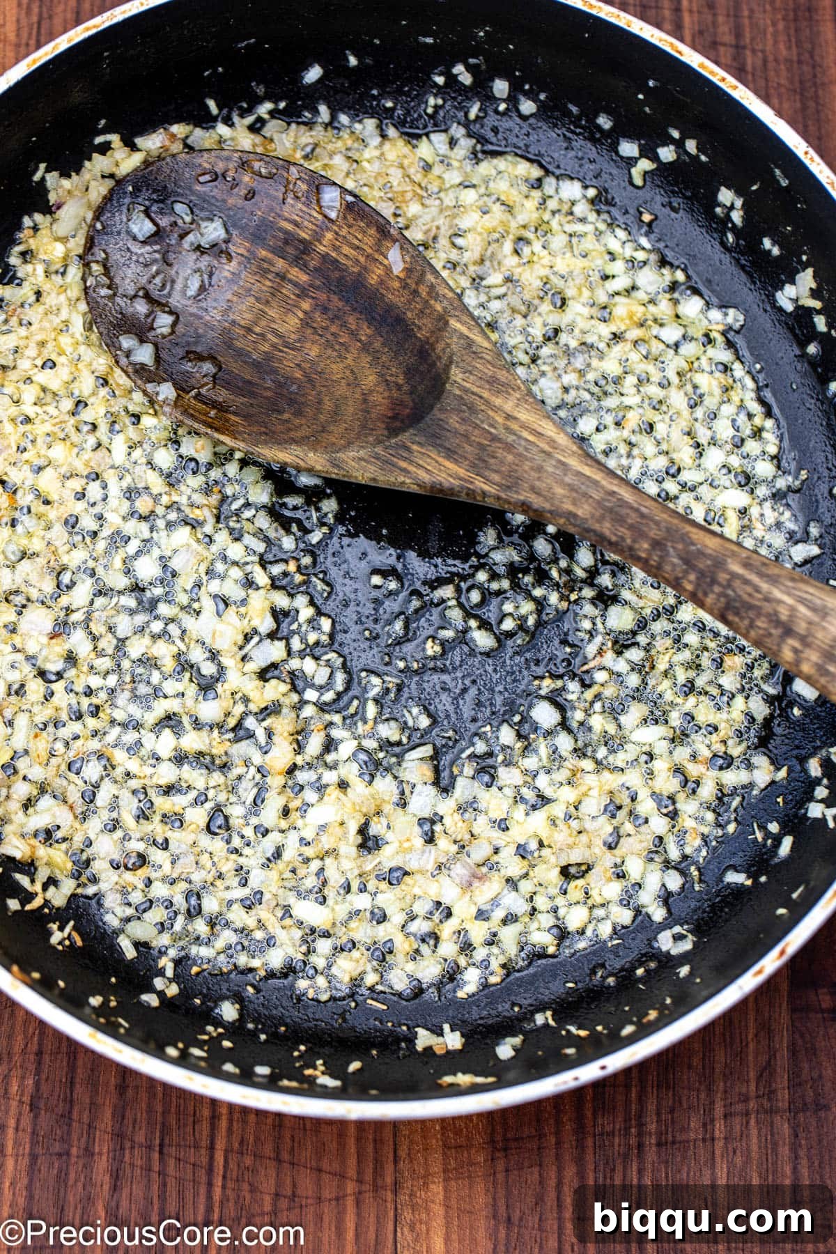 Sautéed shallots and garlic sizzling in a skillet, forming the aromatic base of the sauce.
