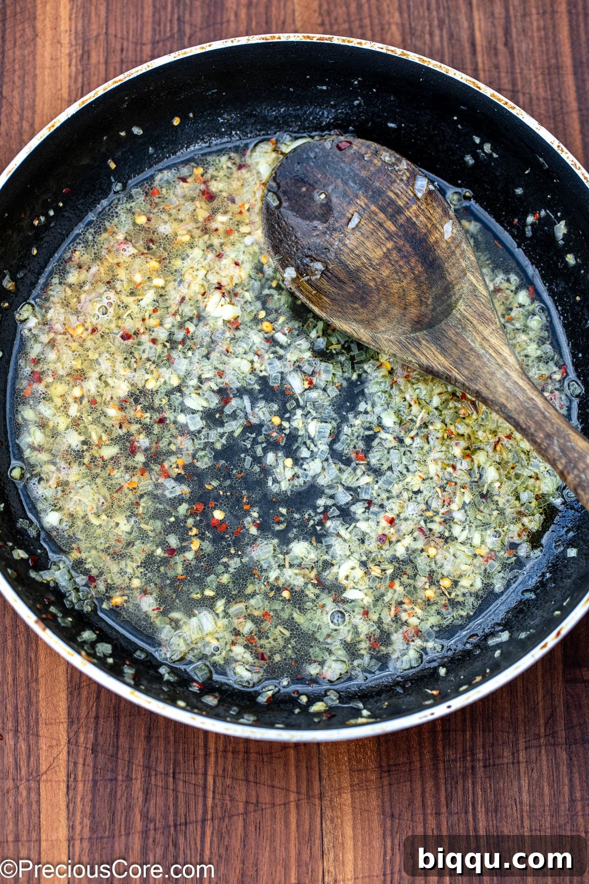 White wine sauce with garlic and shallots simmering in a skillet, creating a flavorful broth.