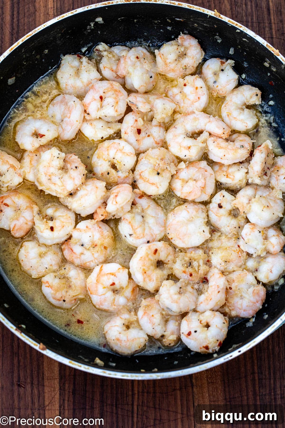Perfectly cooked shrimp in a skillet with rich white wine sauce, glistening and ready to serve.