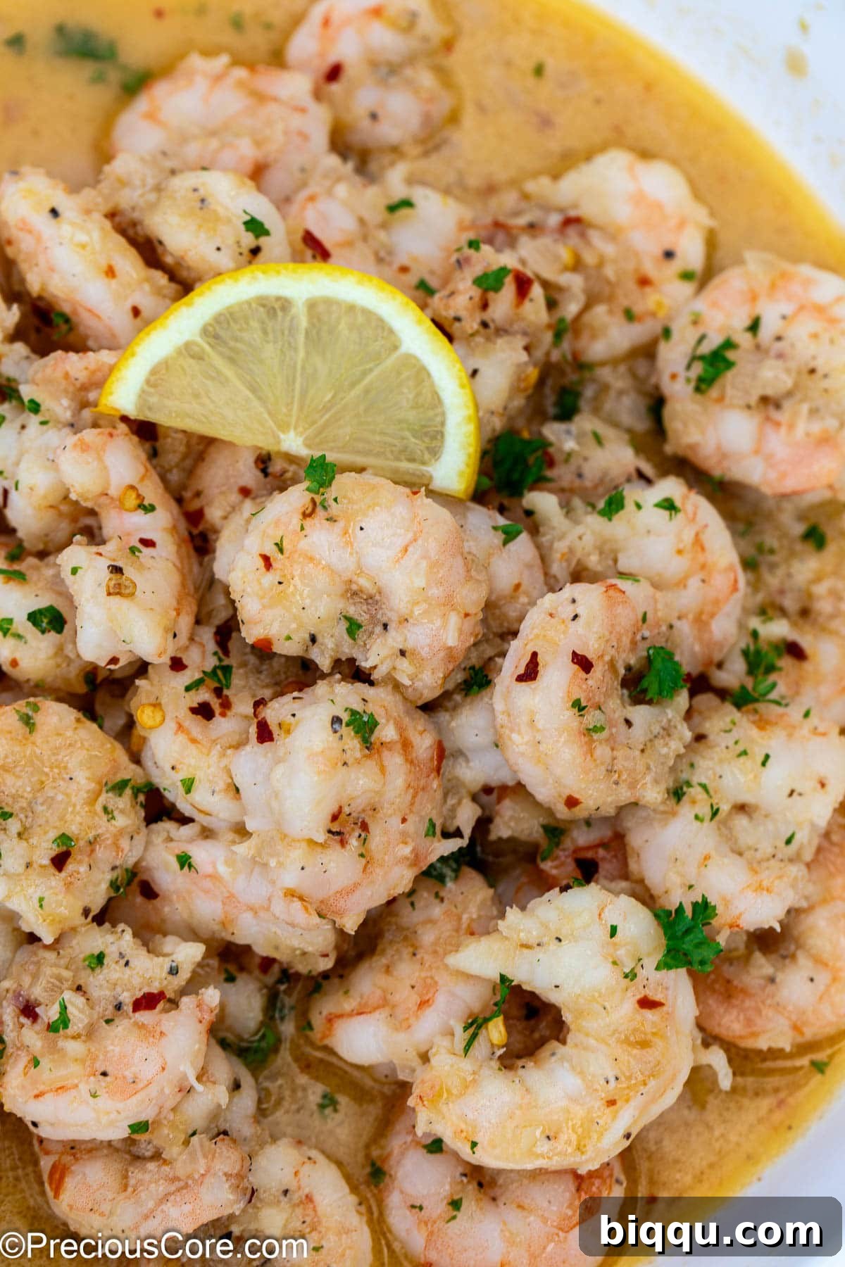 Close-up shot of perfectly cooked shrimp garnished with a vibrant lemon slice and fresh herbs.
