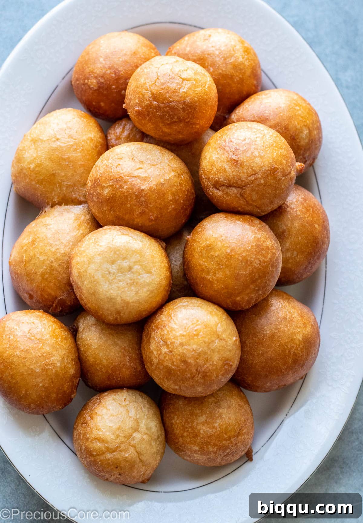 Freshly made, golden-brown Puff Puff arranged on a white serving tray, ready to be enjoyed.