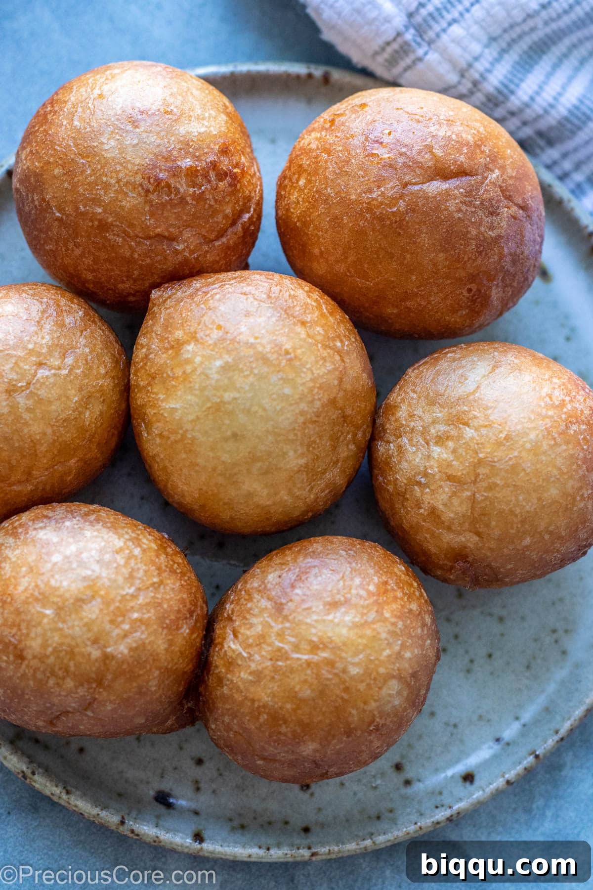 A serving of freshly fried, perfectly golden Puff Puff on a small white plate, highlighting its appetizing texture.