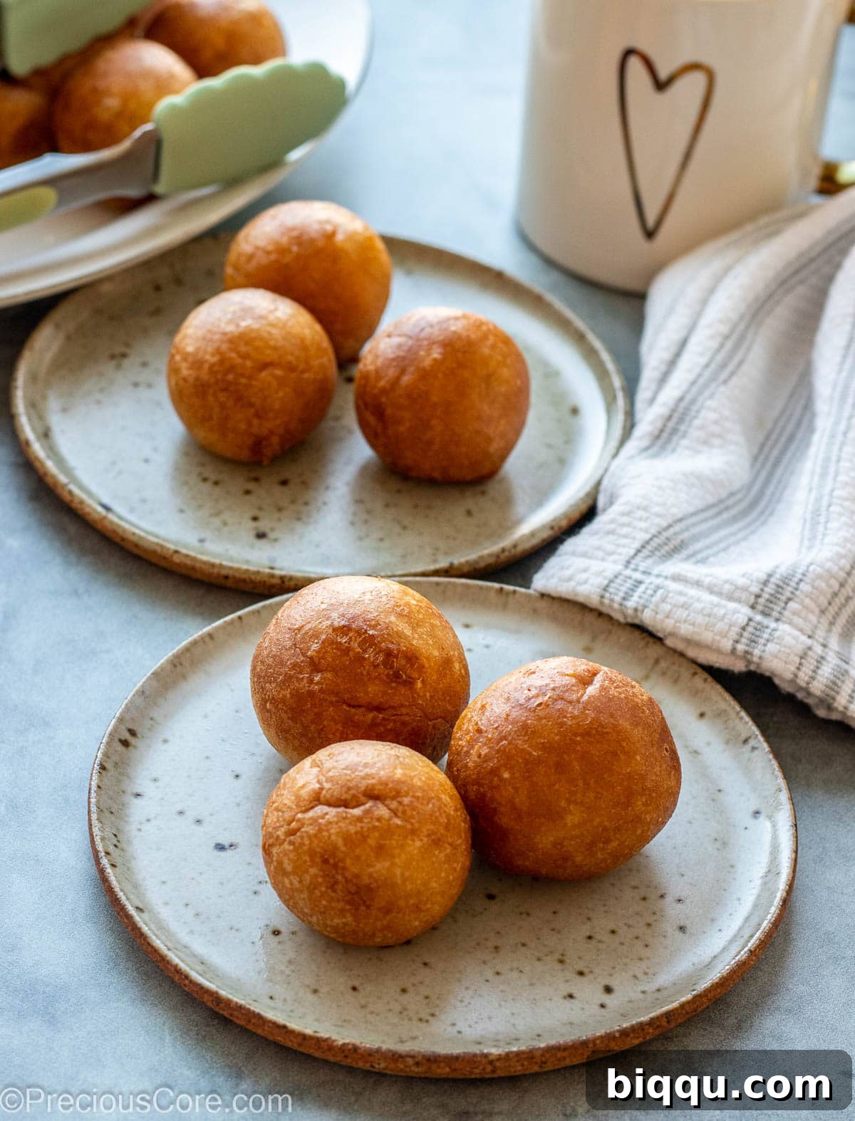 Two small plates featuring African snacks, including light, fluffy Puff Puff, alongside other fried dough items.