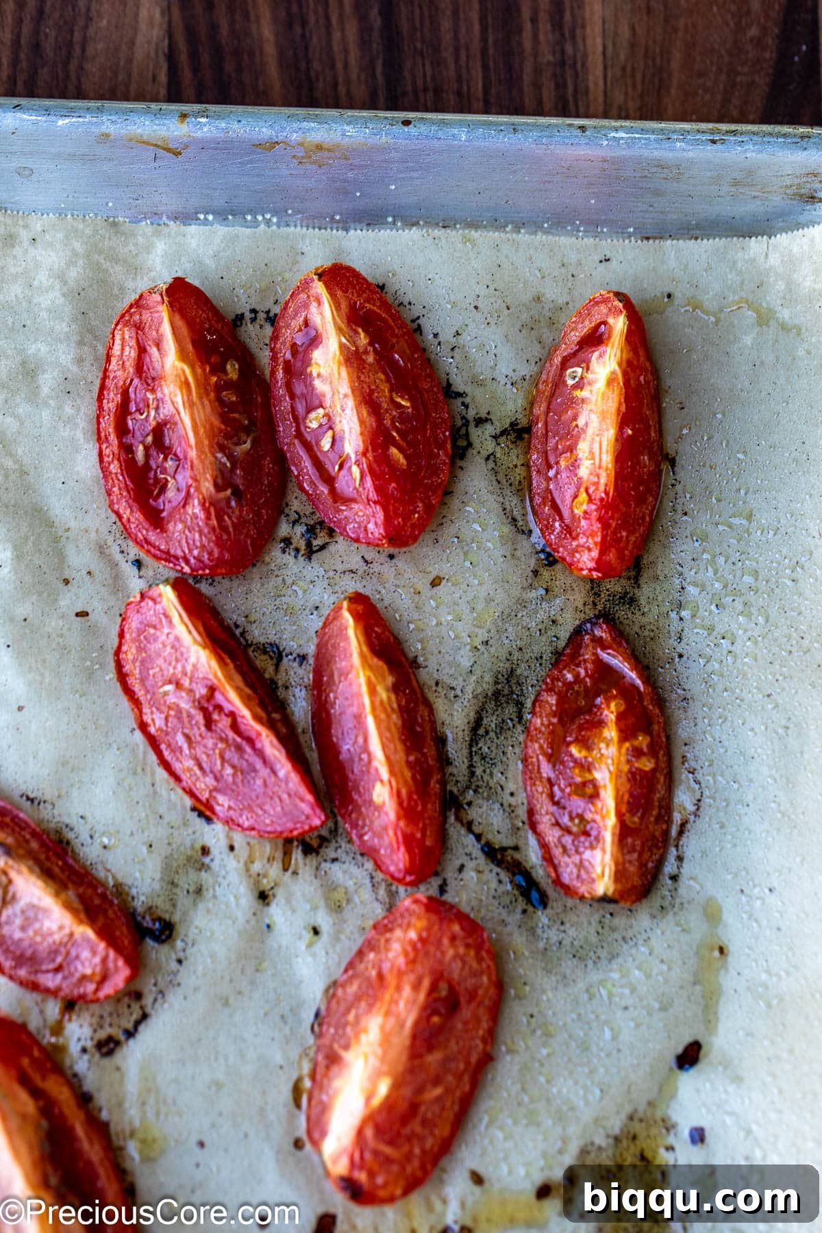 Golden brown roasted tomatoes on a baking sheet lined with parchment paper.