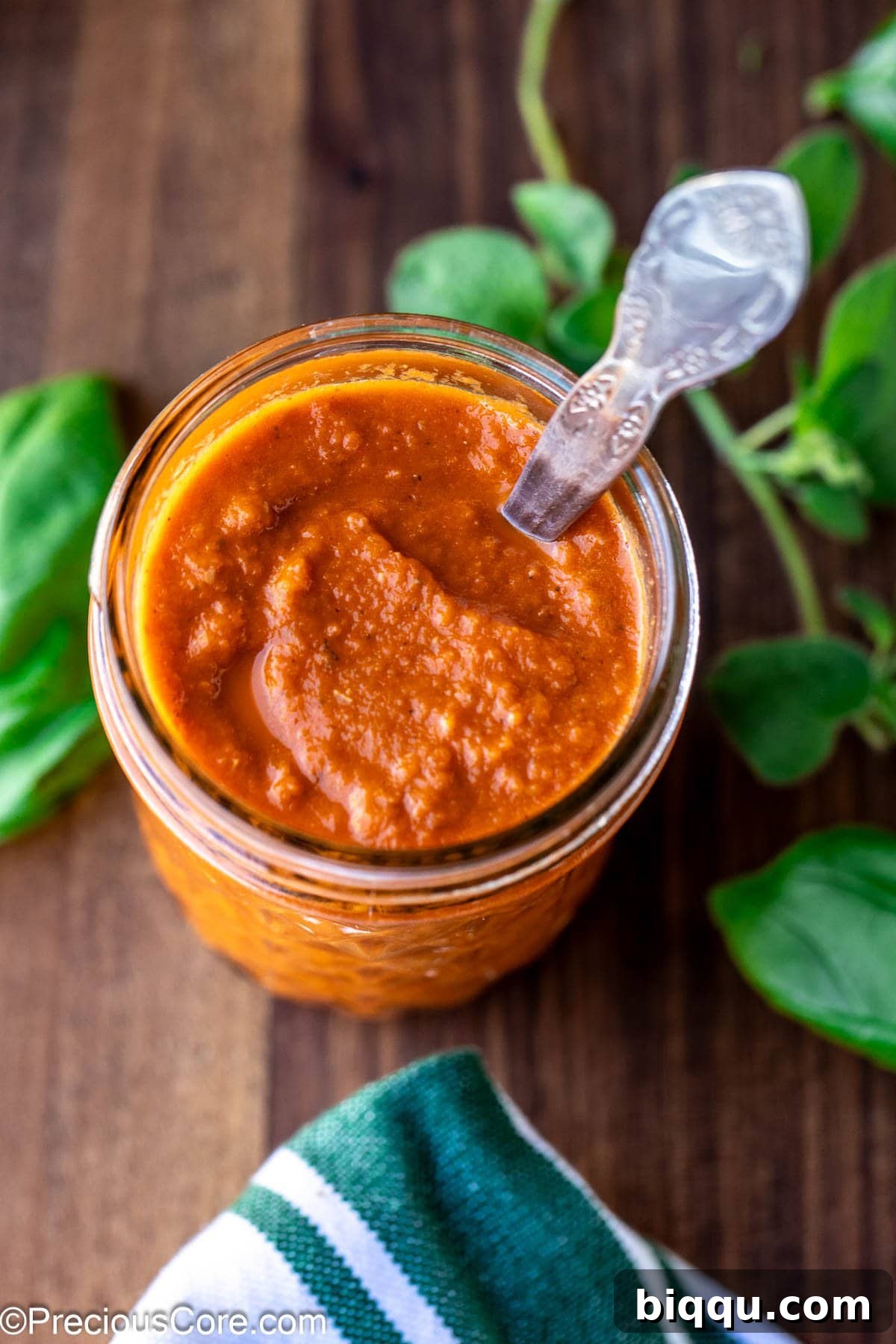 Roasted tomato pizza sauce stored in a clear mason jar, showcasing its rich red color.