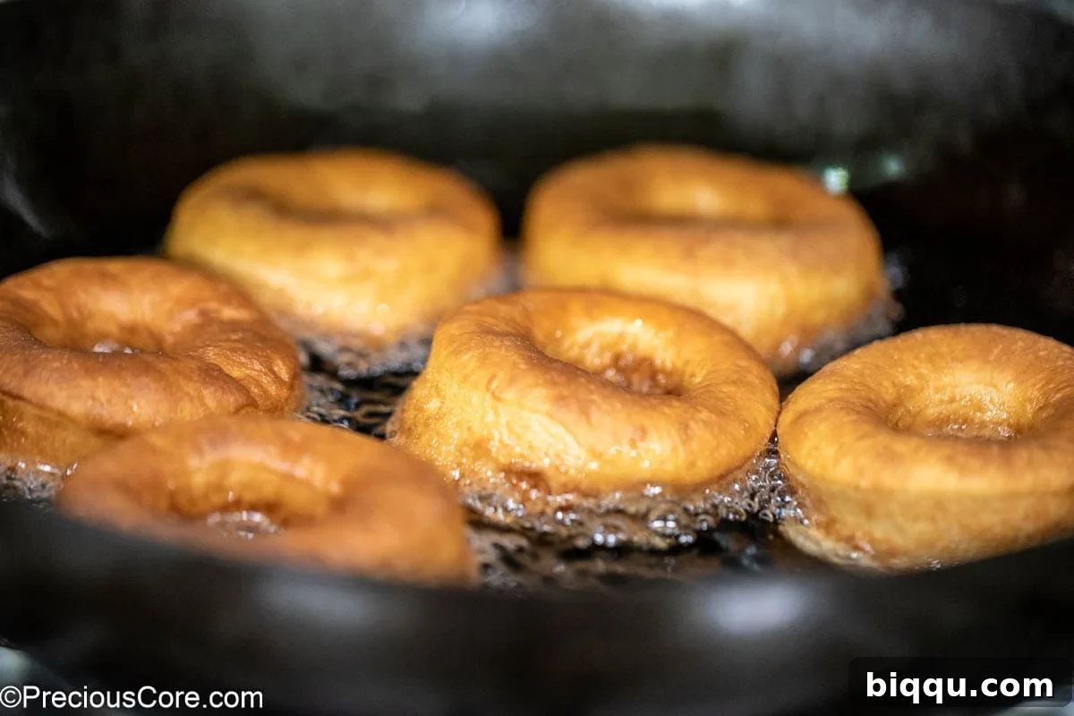 Golden brown donuts frying in oil.