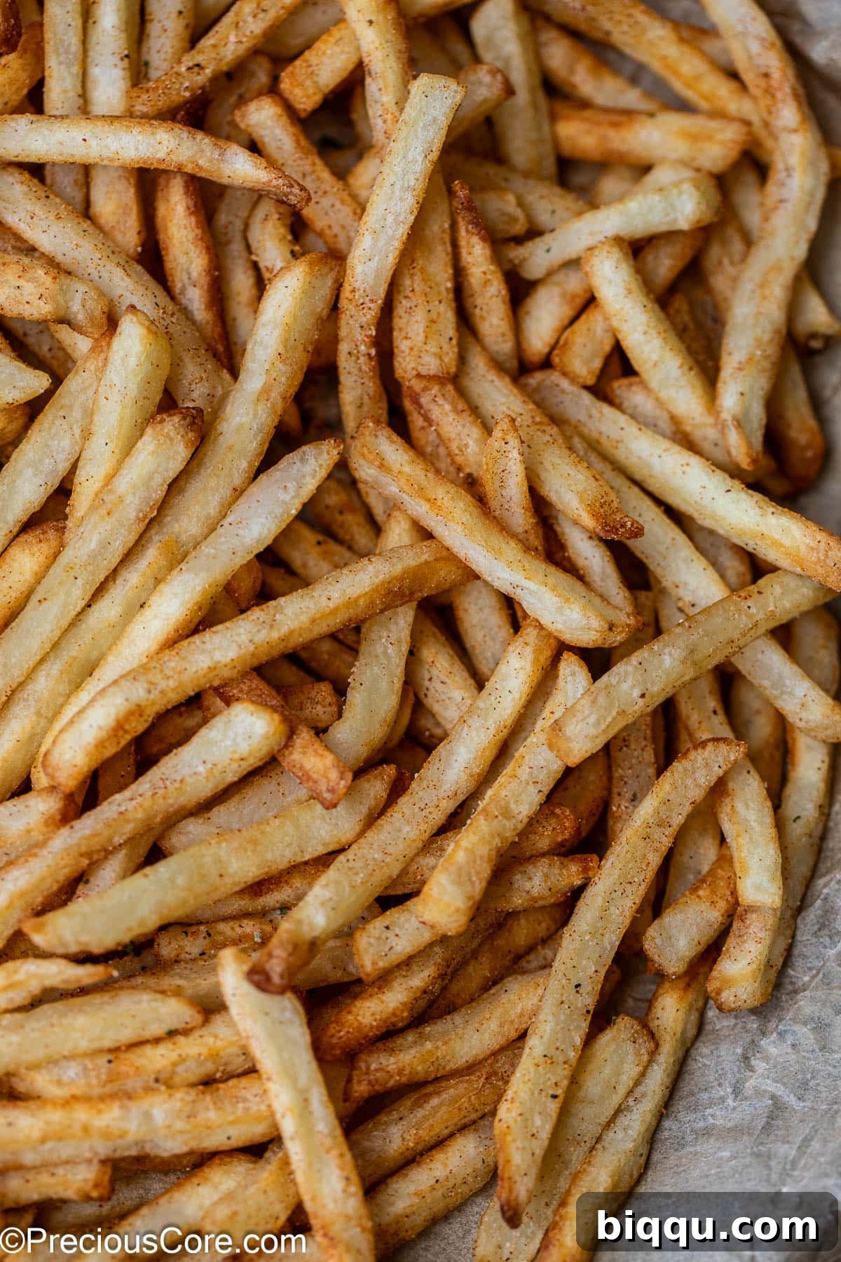 Close-up view of golden French fries with savory seasoning sprinkled generously on top.