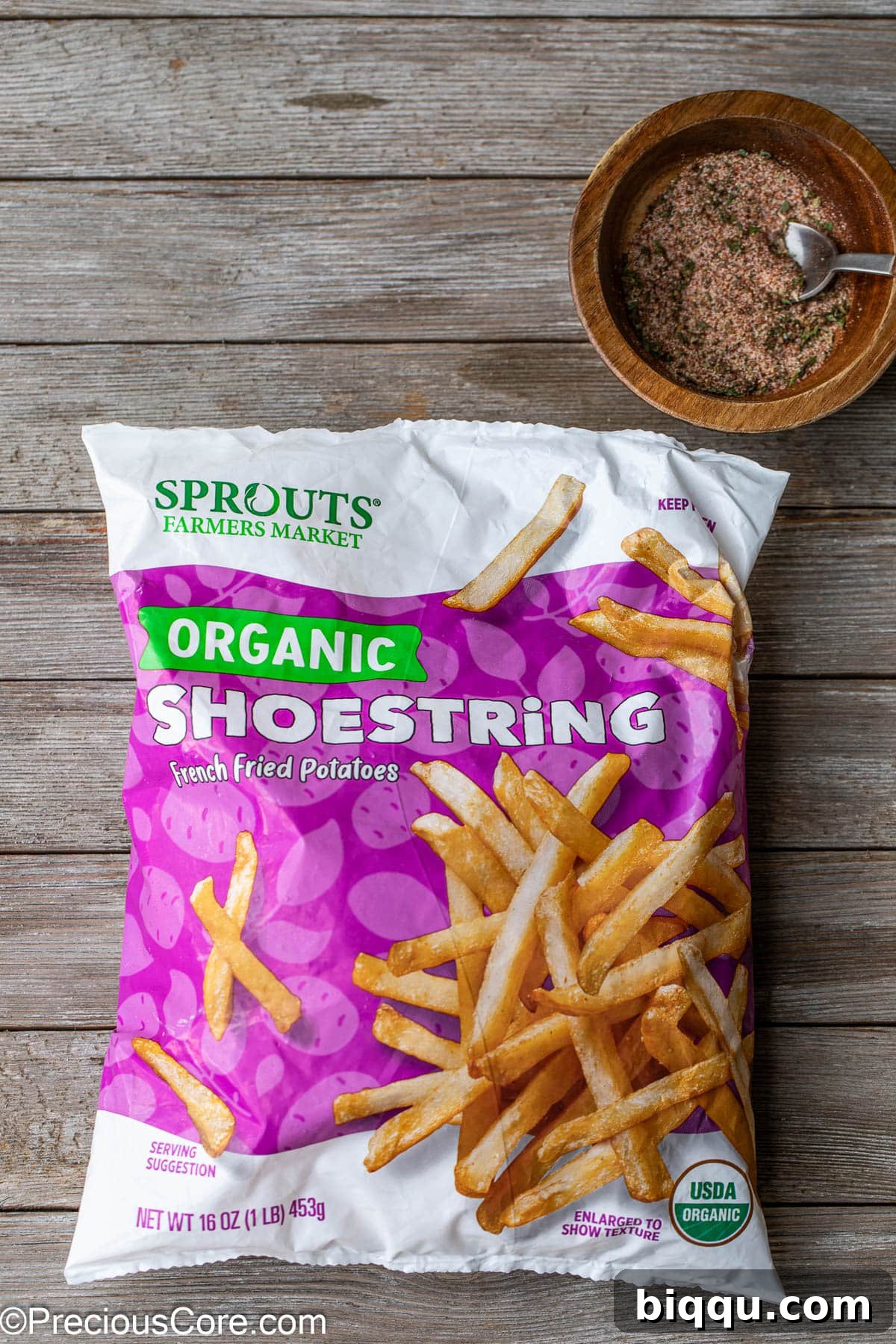 A bag of frozen potato fries next to a small bowl of fry seasoning, ready for preparation.